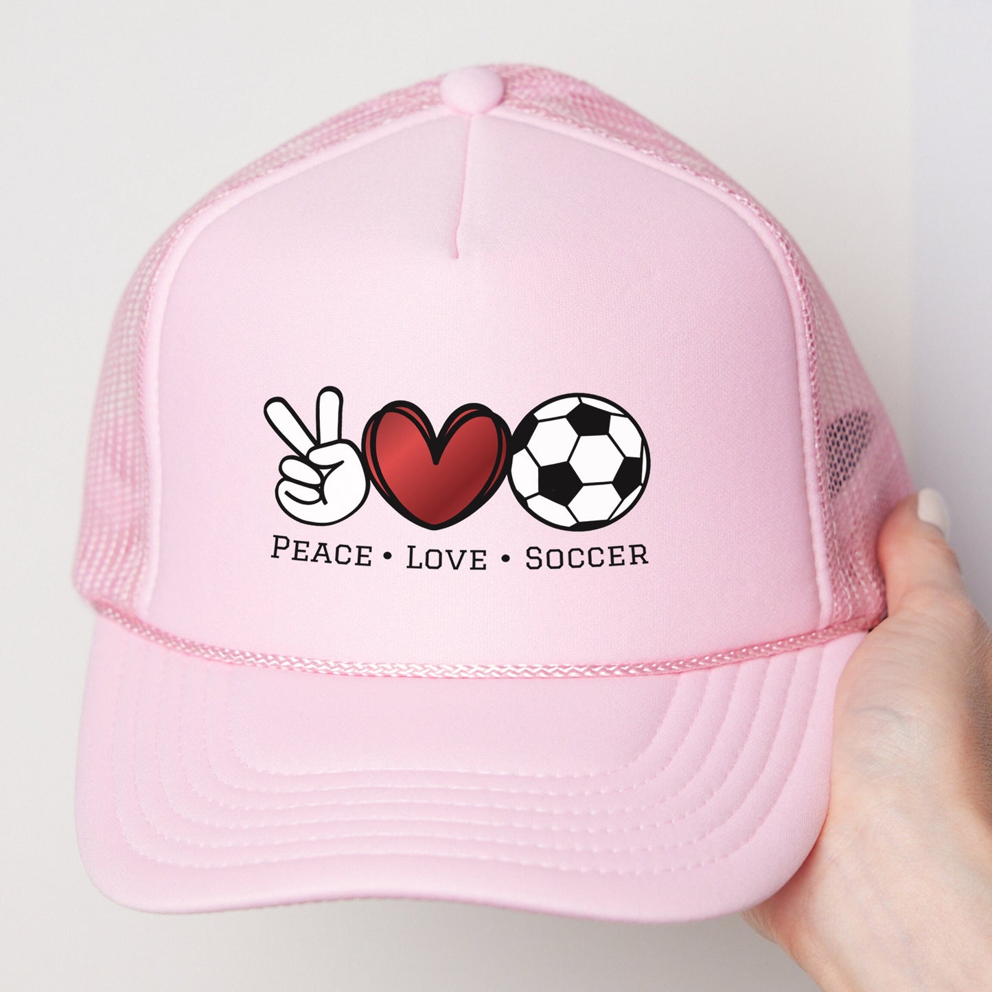 a pink trucker hat with peace love soccer written on it