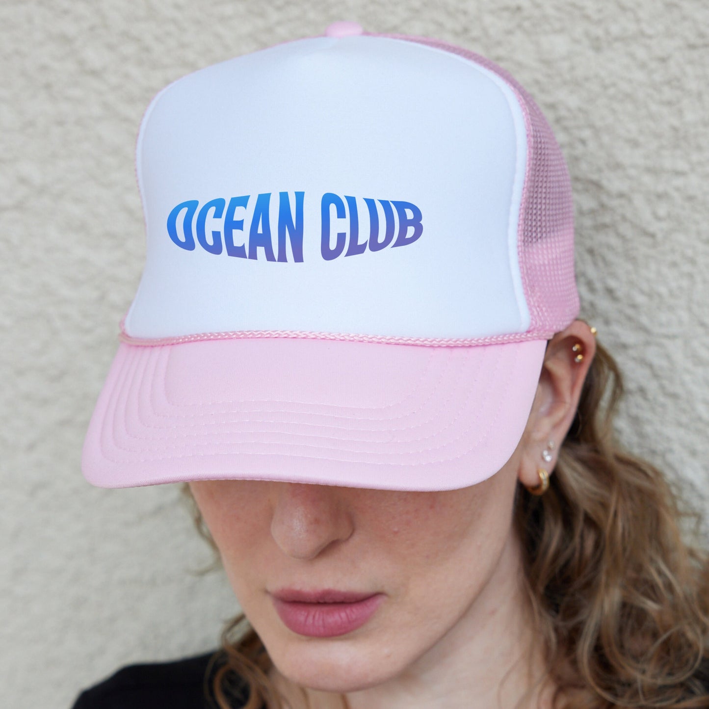 a woman wearing a pink and white trucker hat
