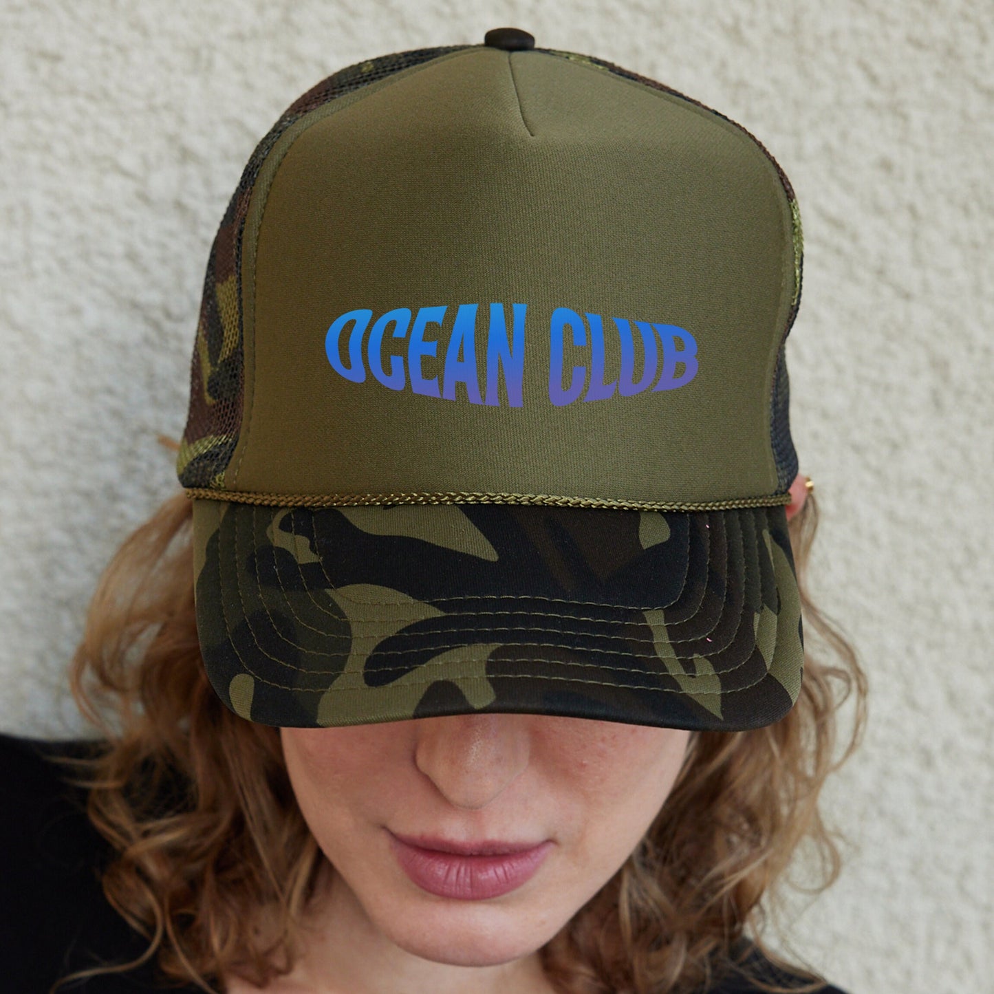 a woman wearing a green and blue ocean club hat