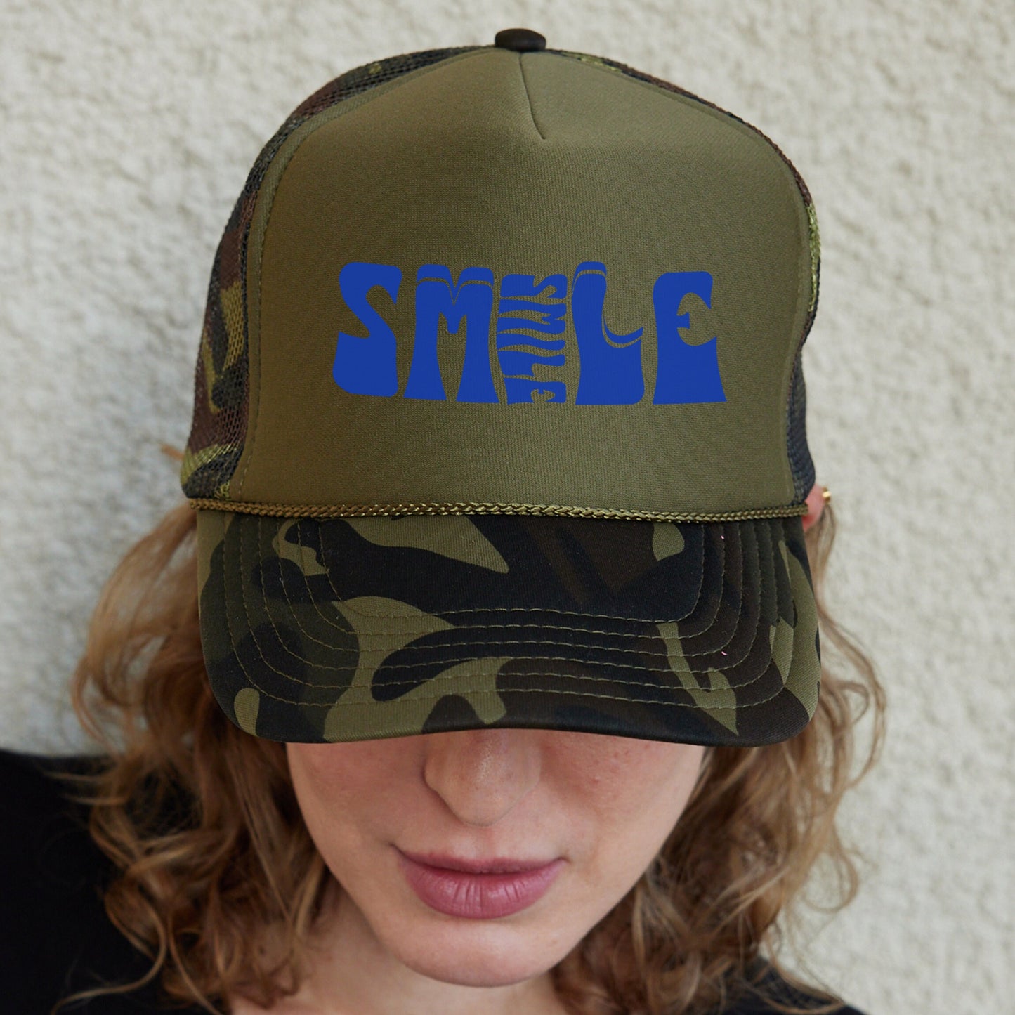 a woman wearing a camo hat with blue letters on it