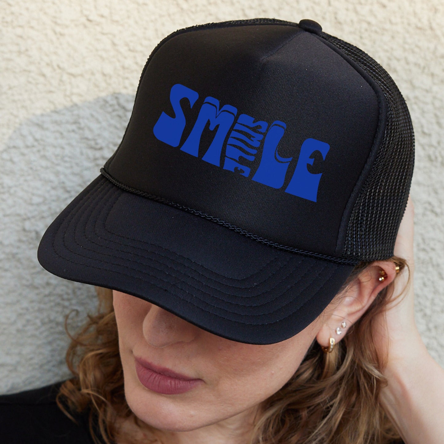 a woman wearing a black hat with blue letters on it
