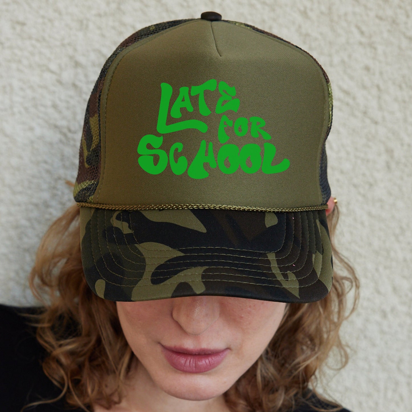 a woman wearing a green and black hat with the words late school on it