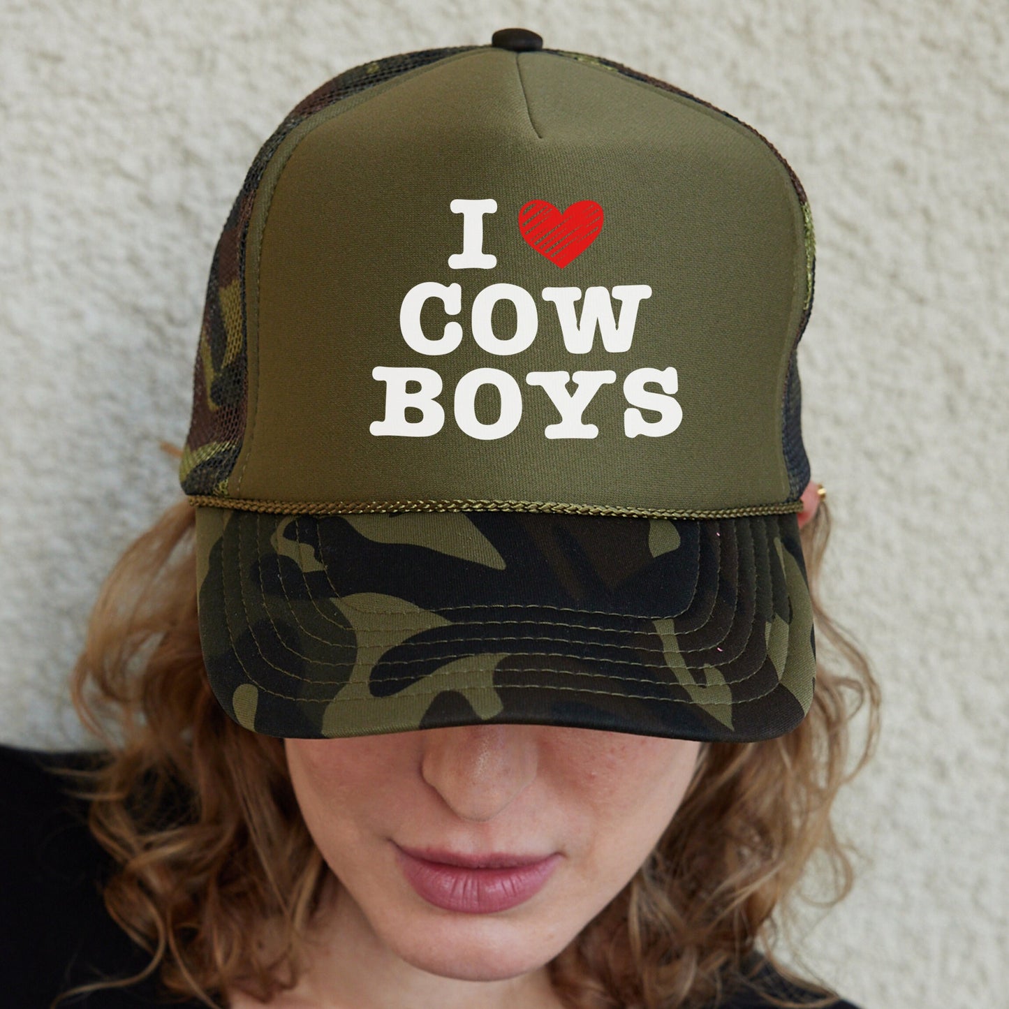 a woman wearing a hat that says i love cow boys