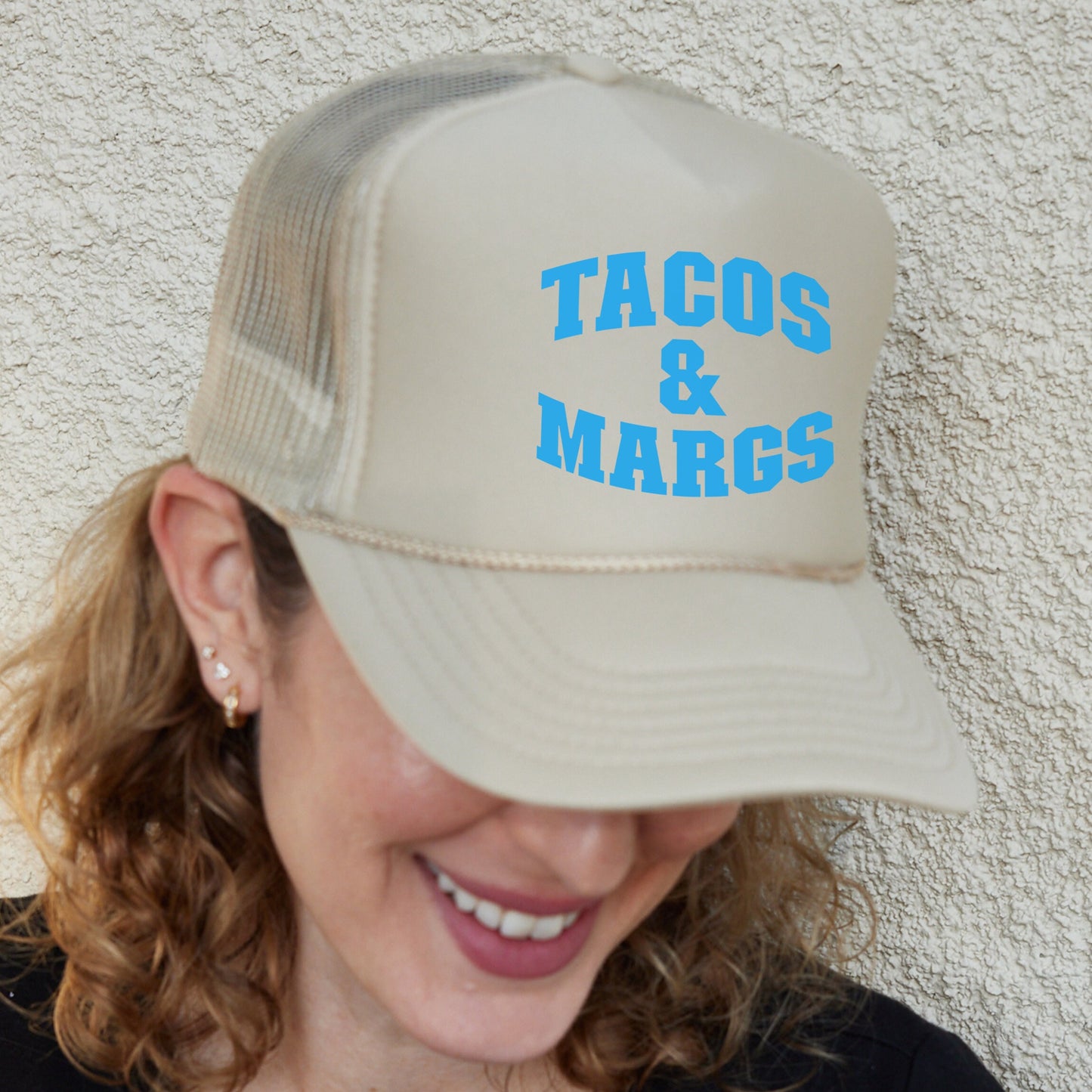 a woman wearing a tan hat with blue tacos and marcs on it