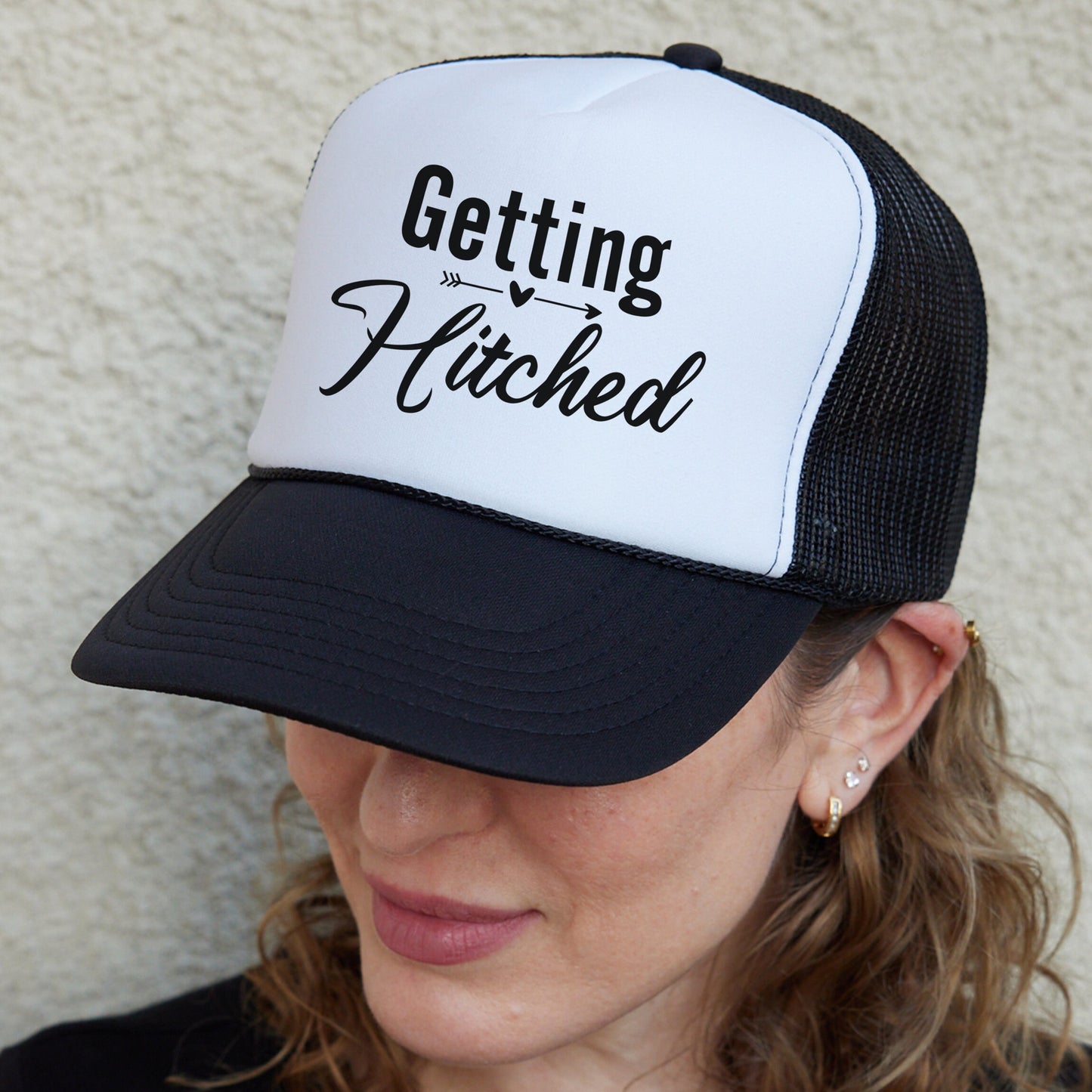 a woman wearing a hat that says getting hitched