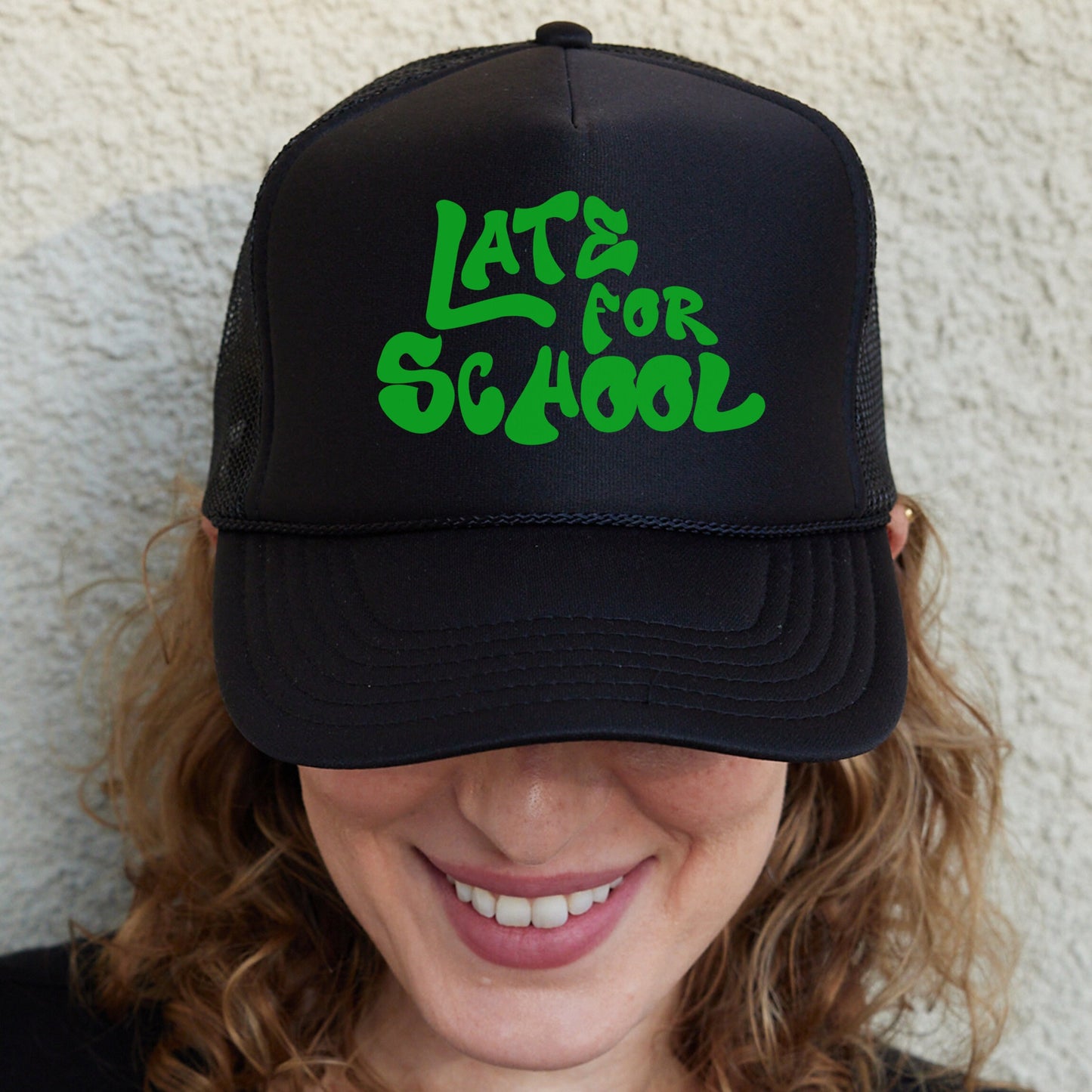 a woman wearing a black hat with green letters on it