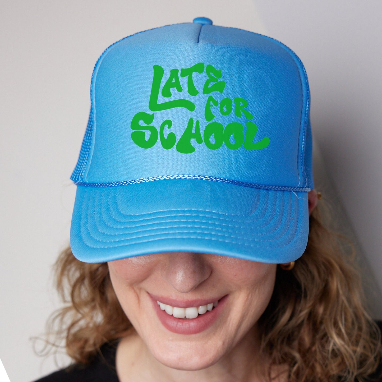 a woman wearing a blue hat with the words late for school on it