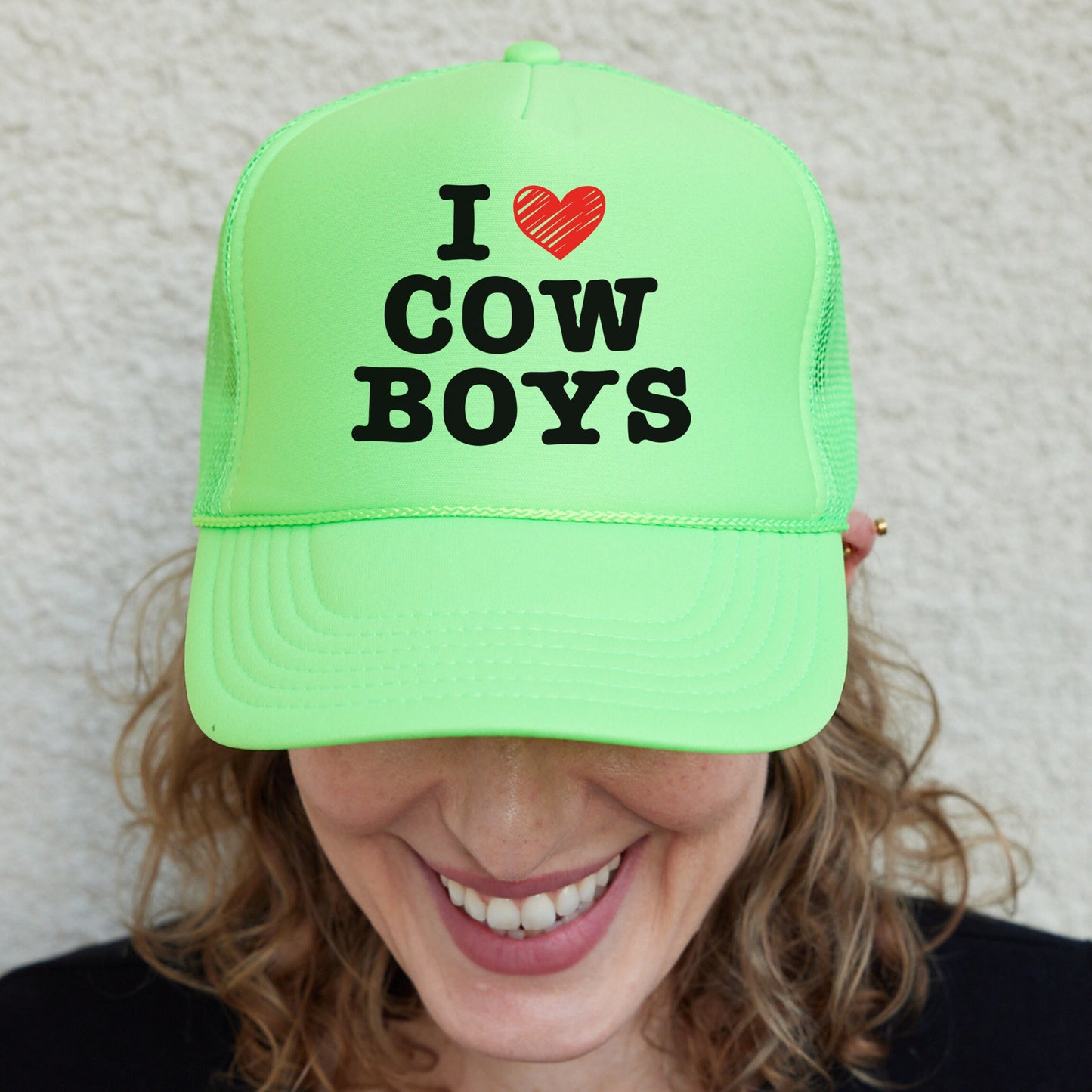 a woman wearing a neon green hat that says i love cow boys