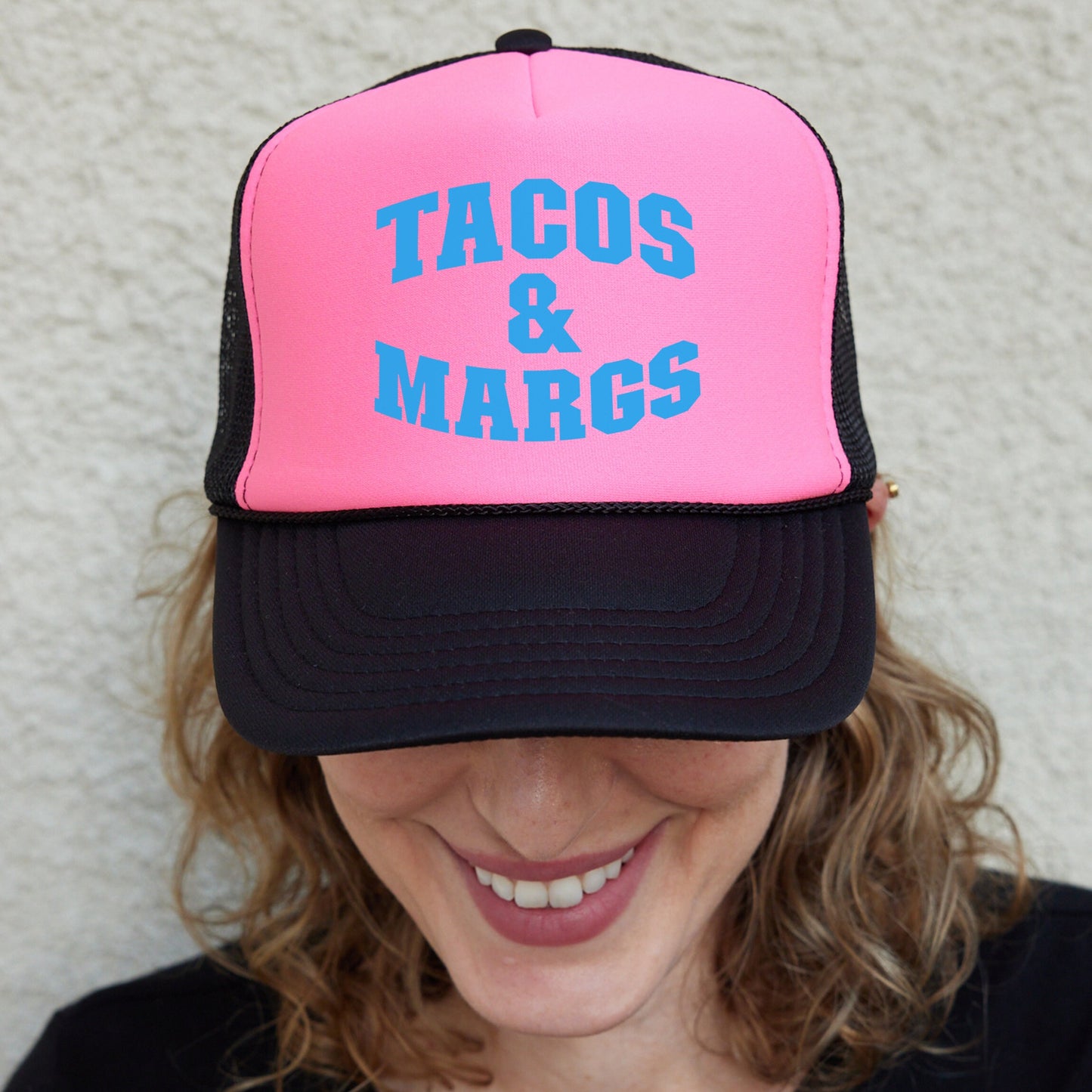 a woman wearing a pink and black trucker hat