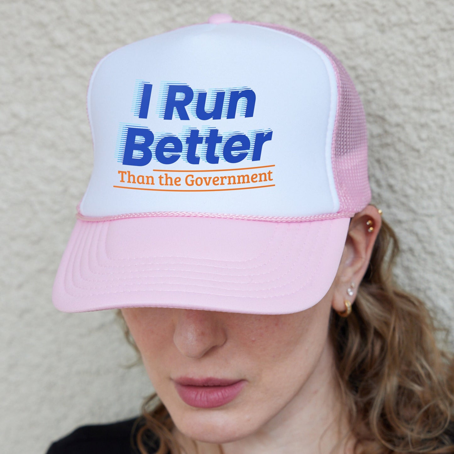a woman wearing a pink and white hat with i run better than the government