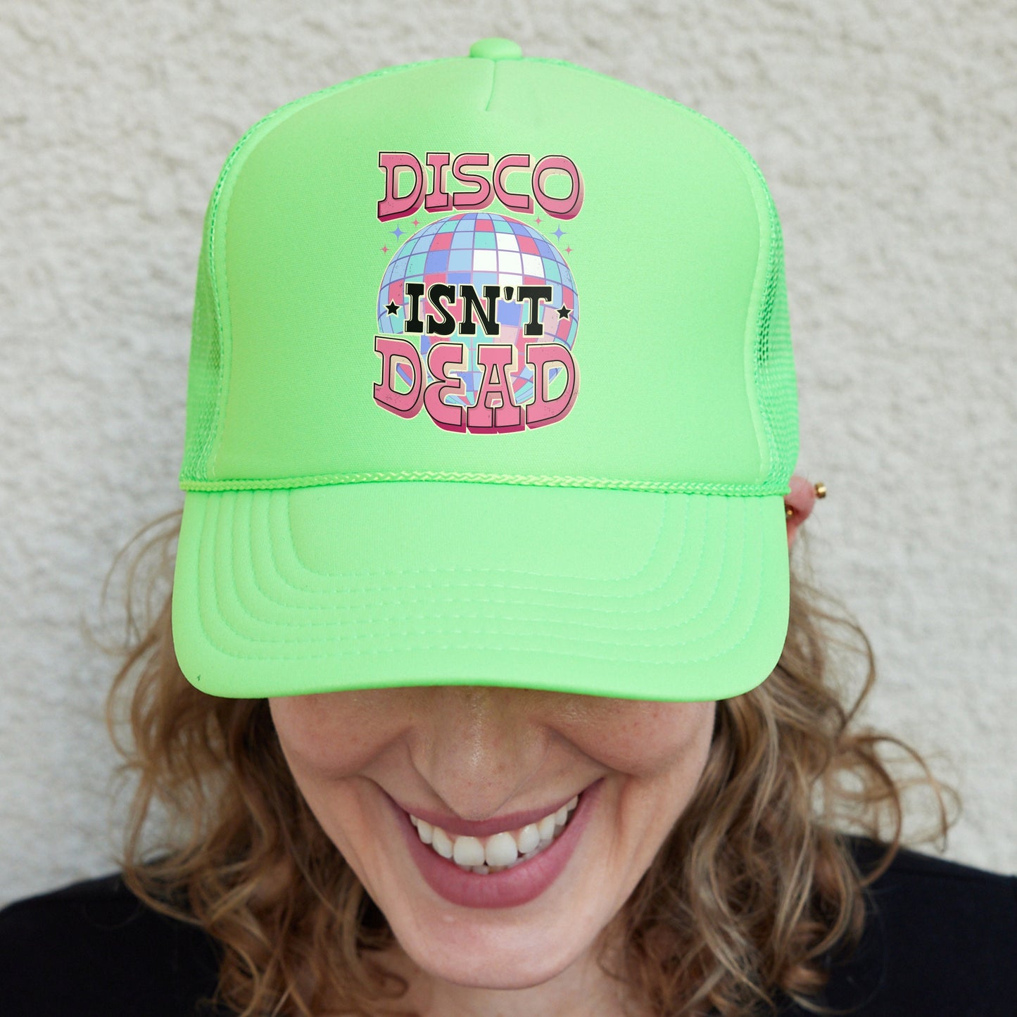 a woman wearing a neon green trucker hat with disco isn't dead on