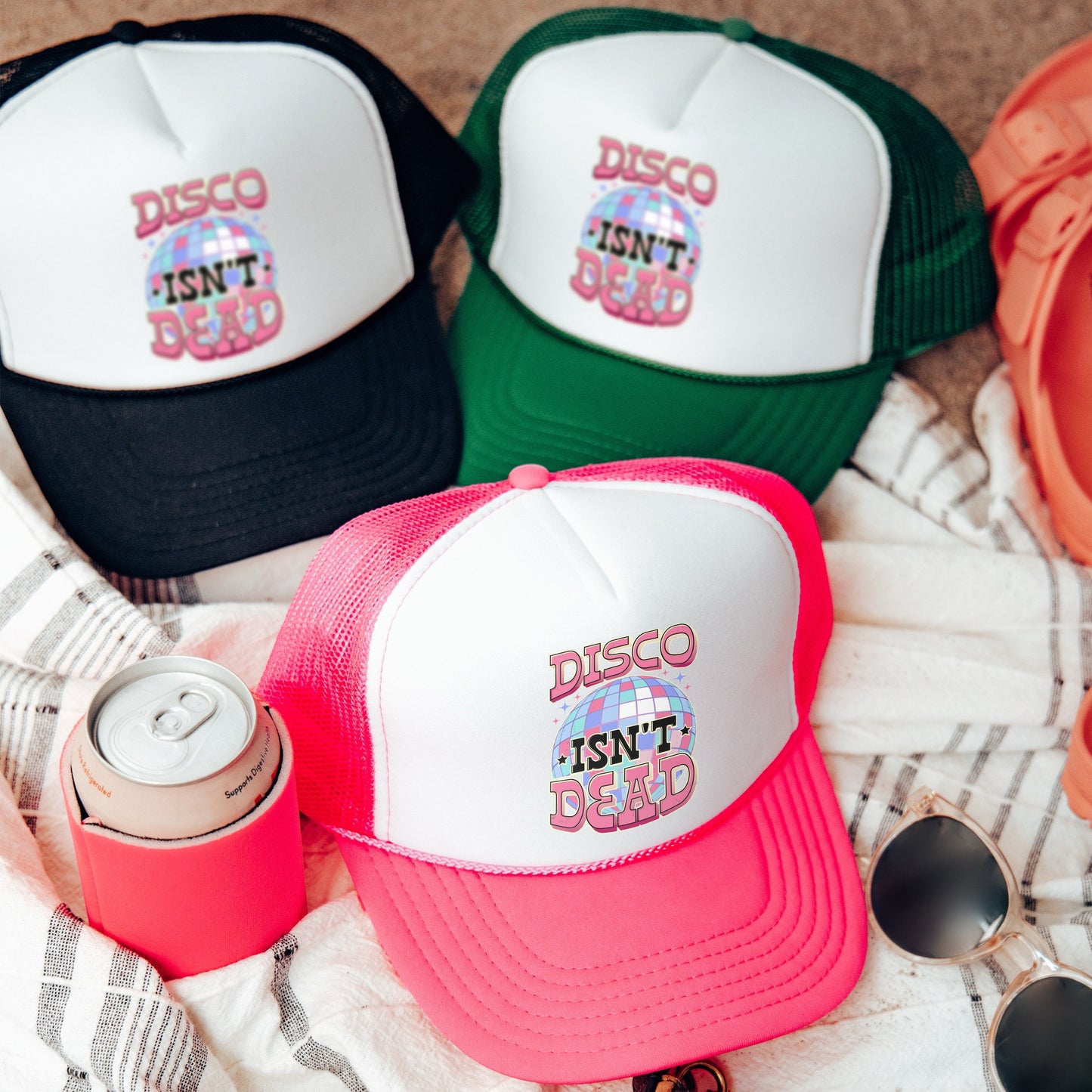 three different colored hats and sunglasses on a blanket