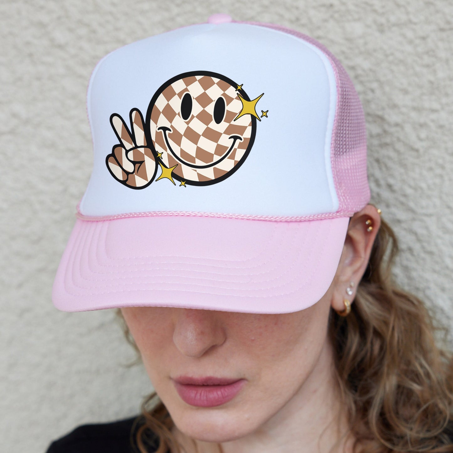 a woman wearing a pink and white hat with a smiley face on it
