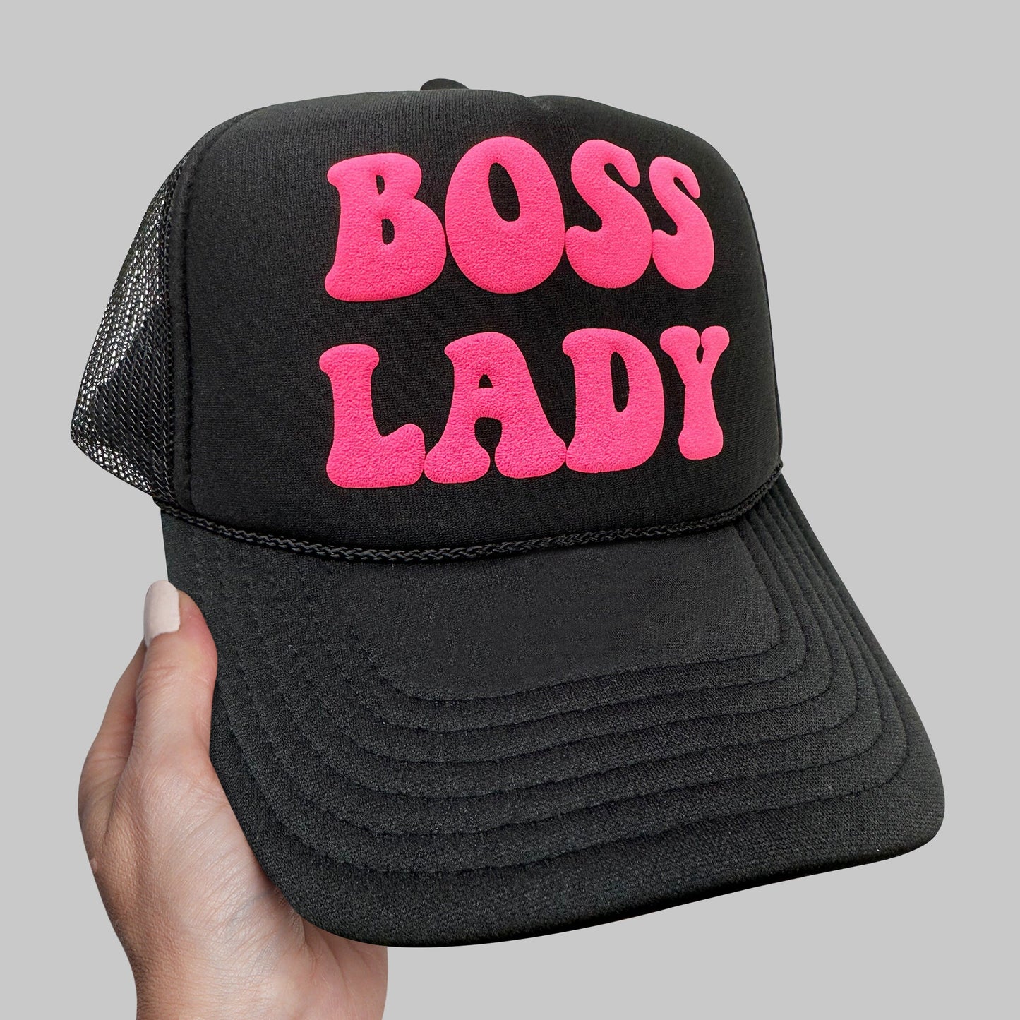 a person holding up a black and pink trucker hat