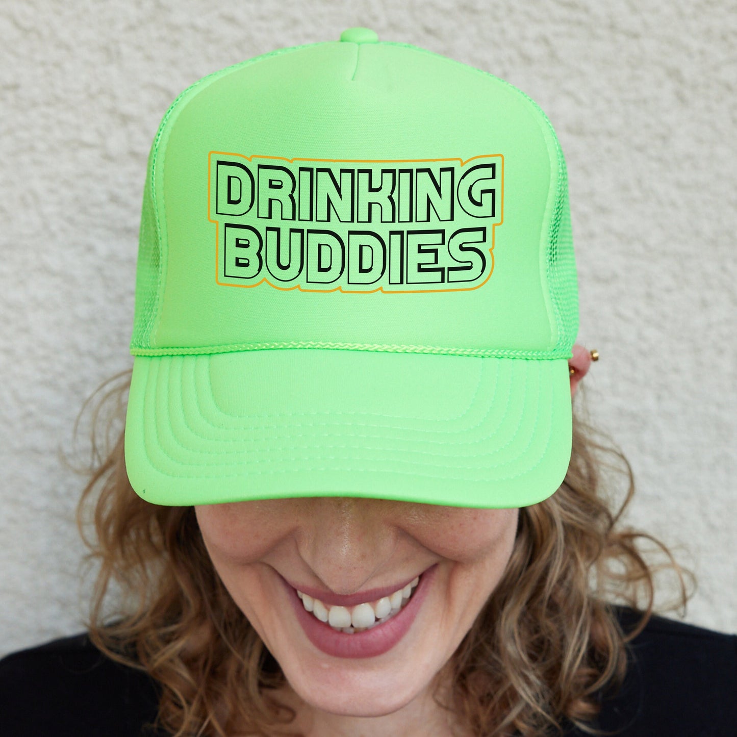 a woman wearing a neon green trucker hat that says drinking buddies
