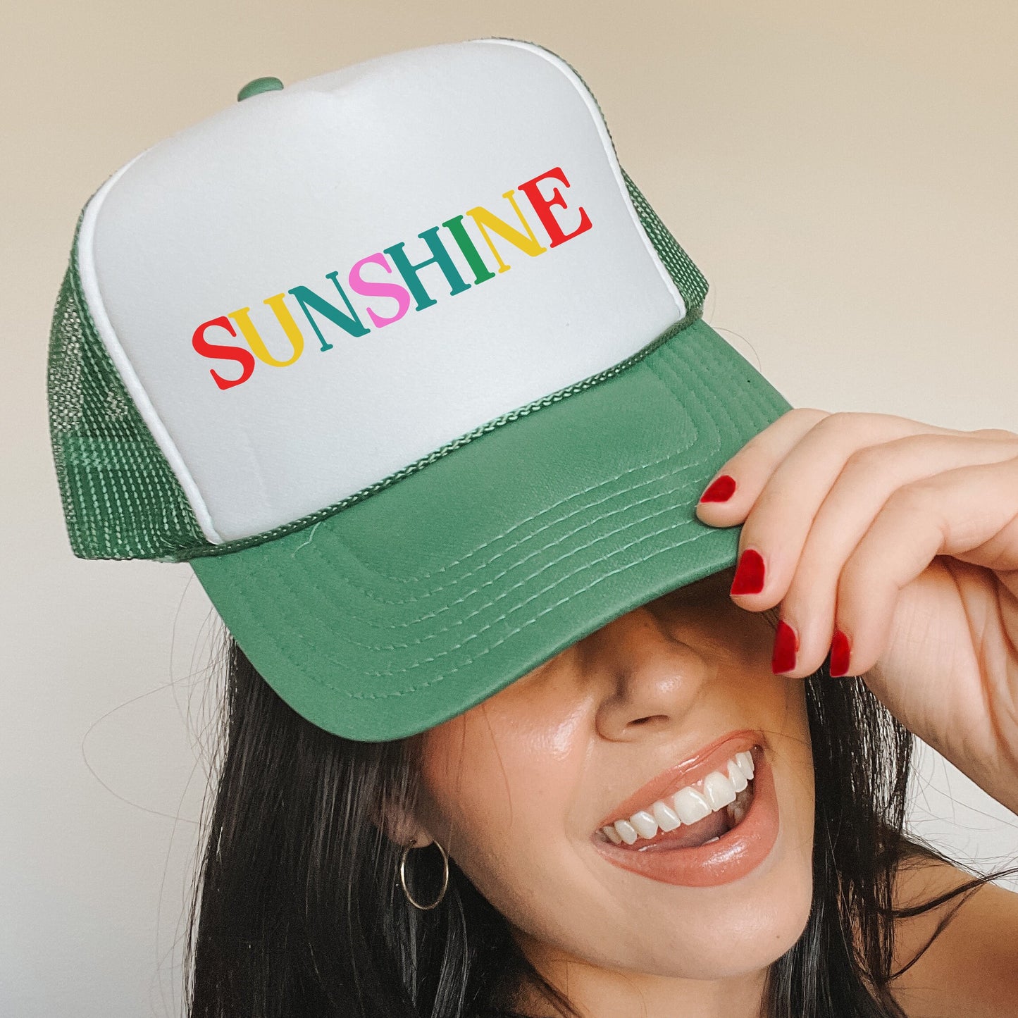 a woman wearing a green and white hat with the word sunshine on it