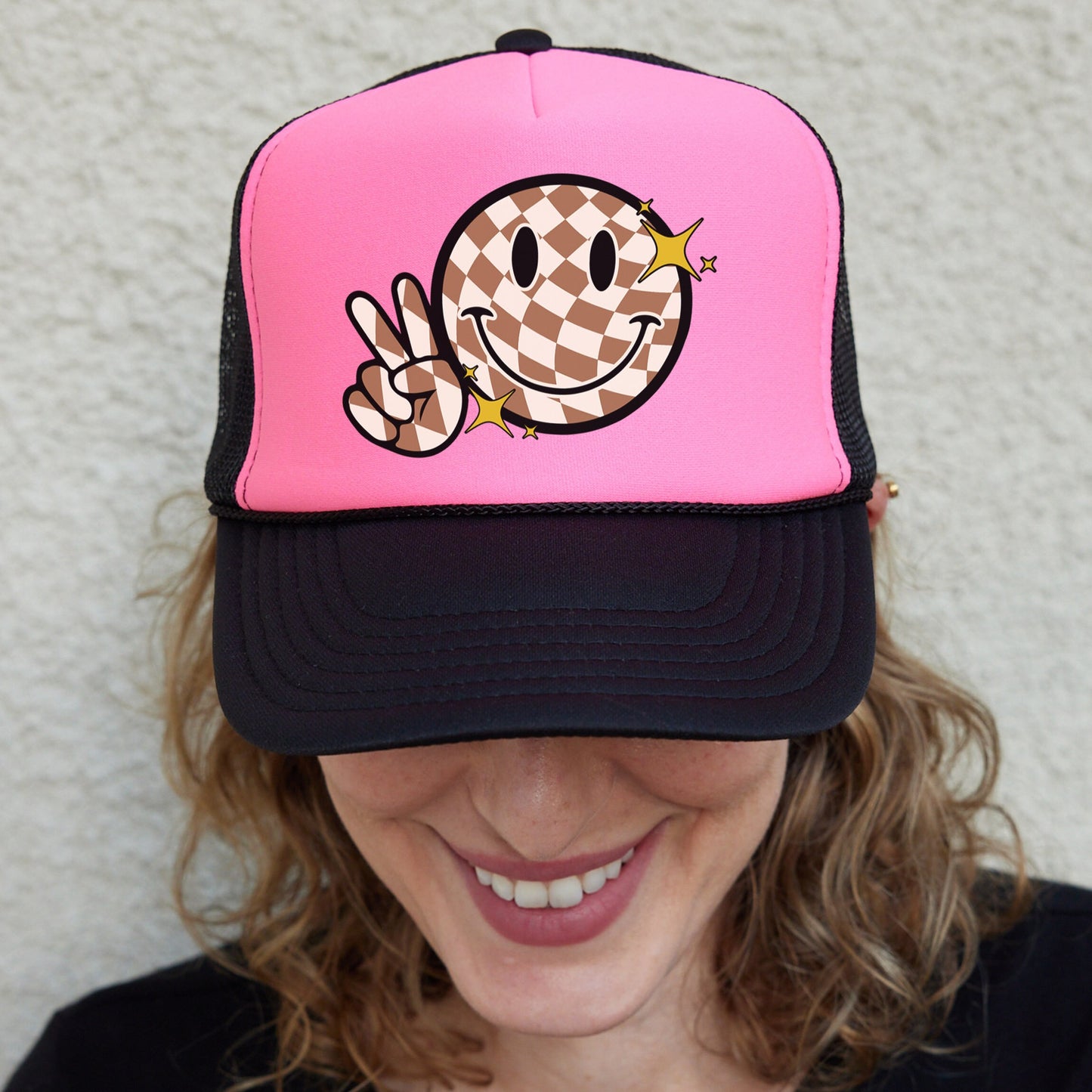 a woman wearing a pink hat with a smiley face on it