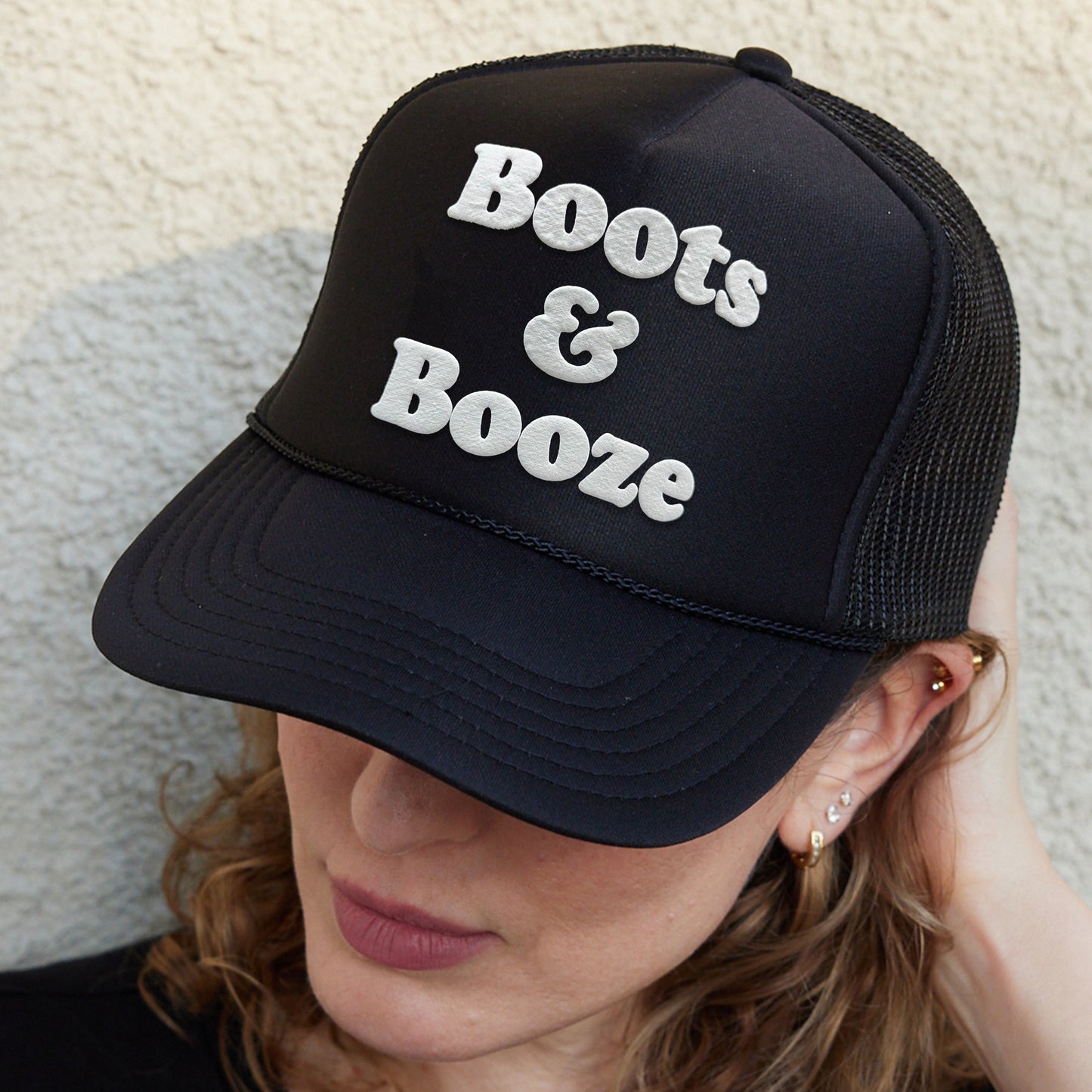 a woman wearing a hat that says boots and booze