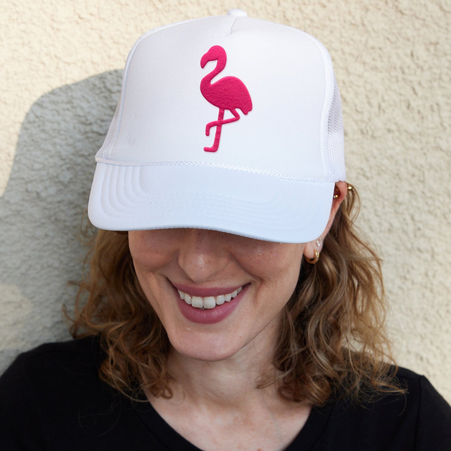 a woman wearing a white hat with a pink flamingo on it