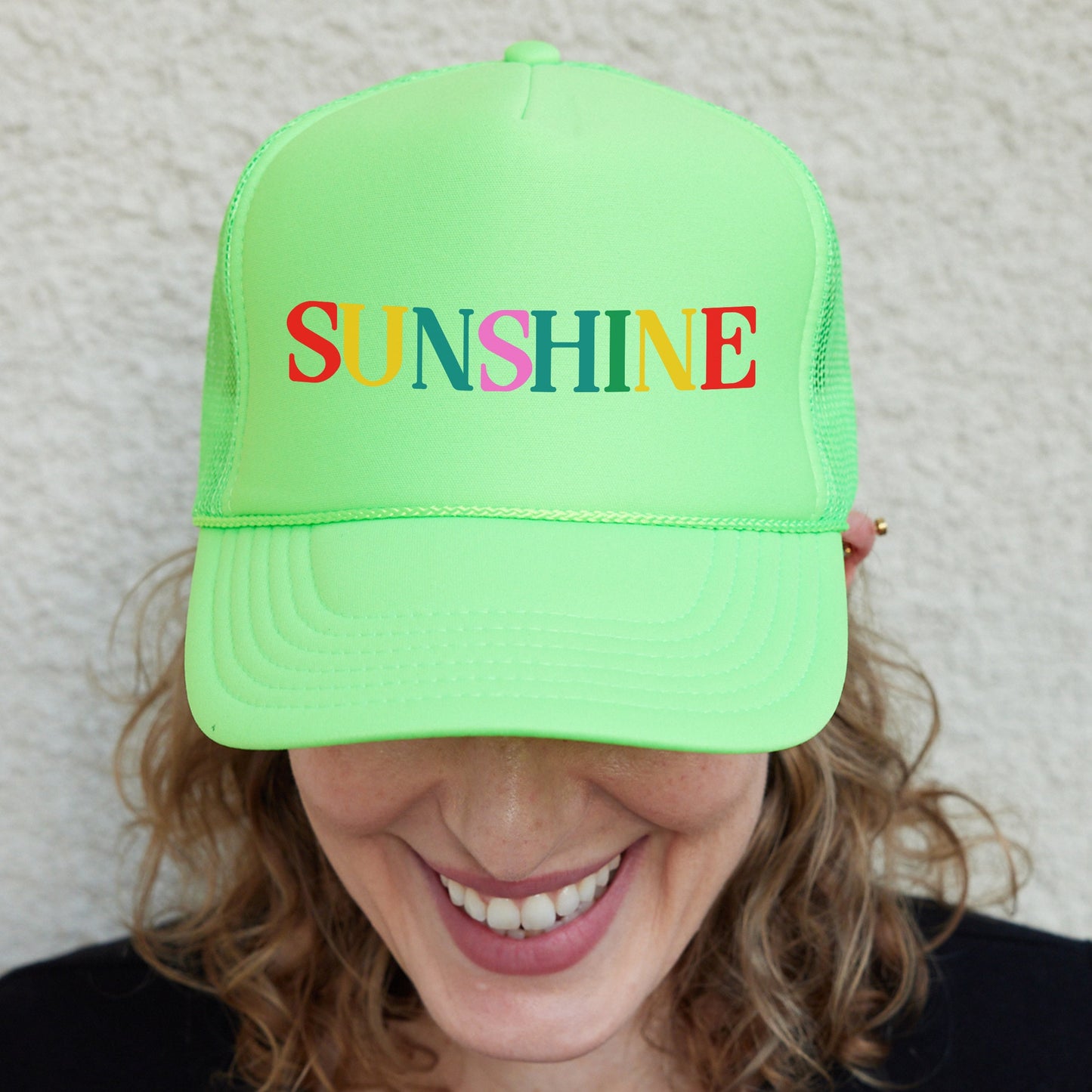 a woman wearing a neon green hat with the word sunshine printed on it