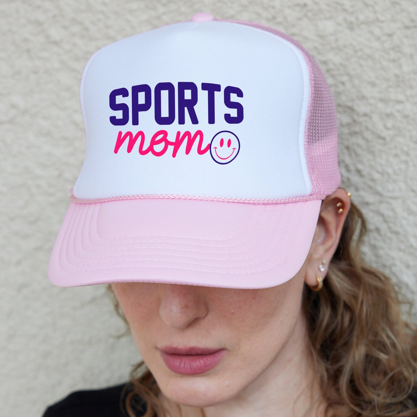 a woman wearing a pink and white sports mom hat