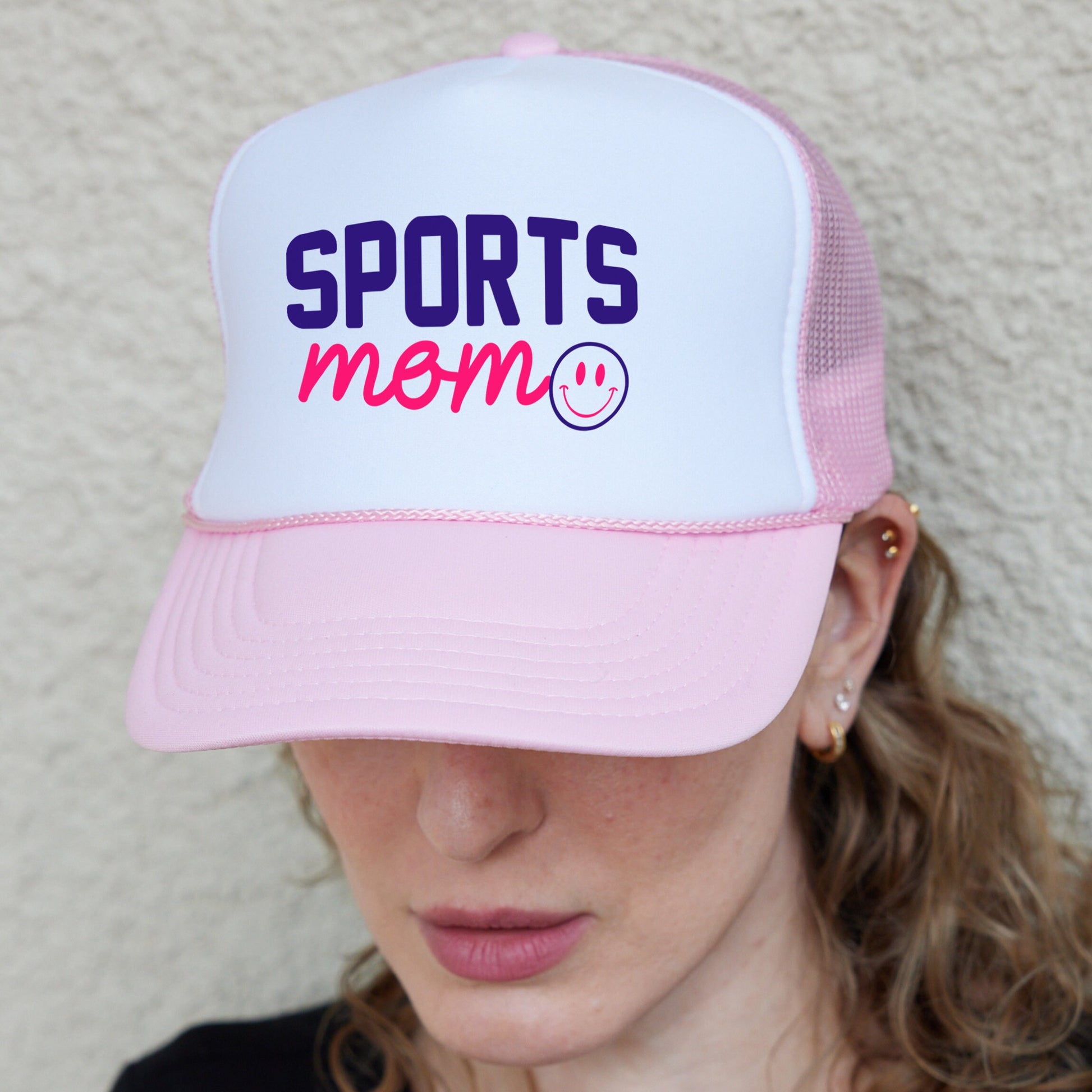 a woman wearing a pink and white sports mom hat