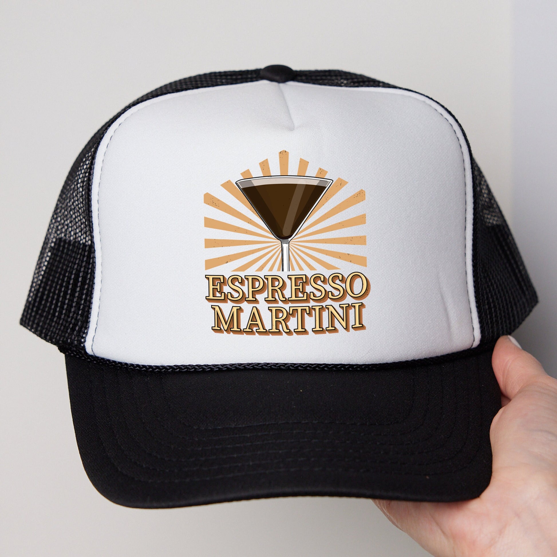 a person holding a trucker hat that says espresso martini