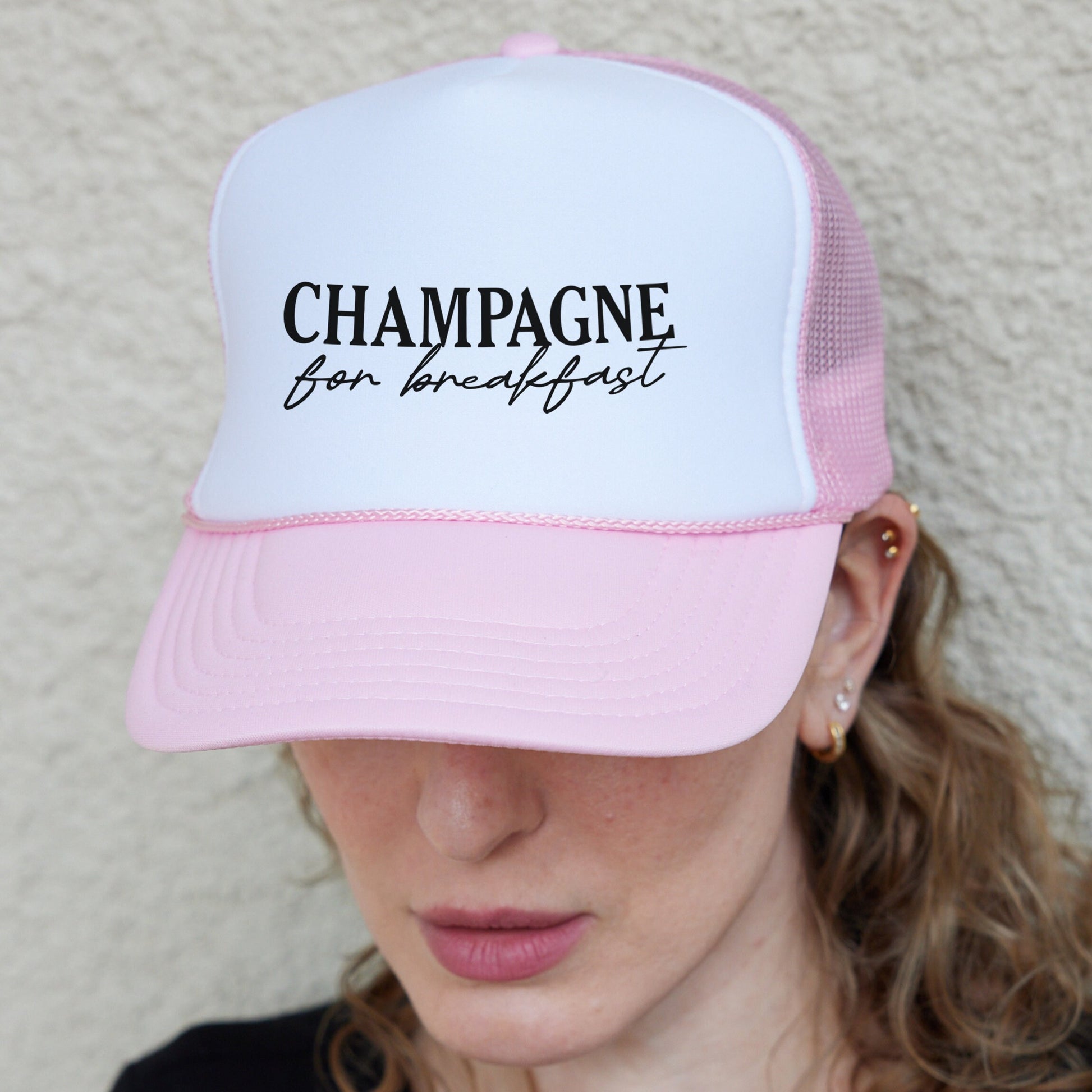 a woman wearing a pink and white hat with the words champagne on it