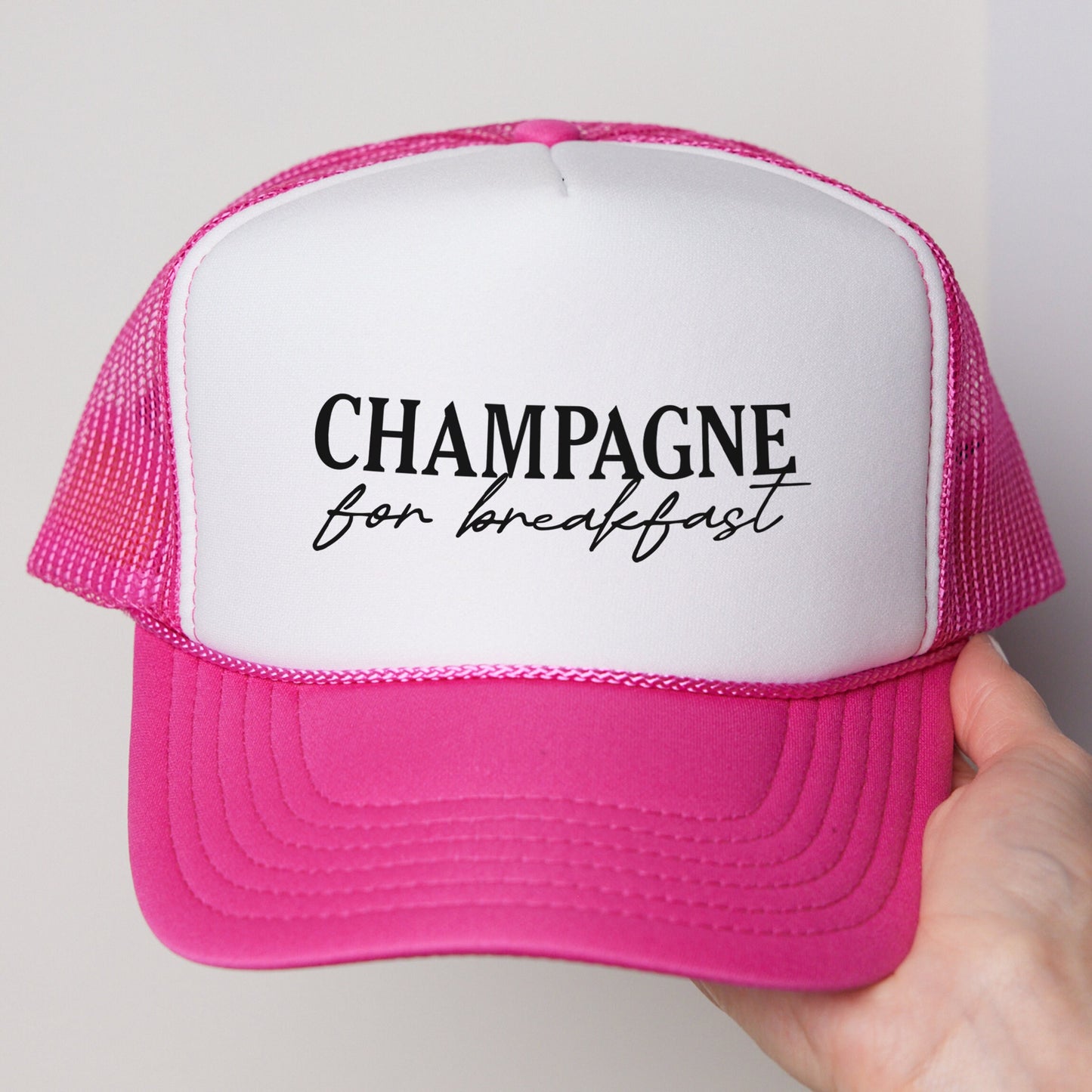 a person holding a pink and white trucker hat