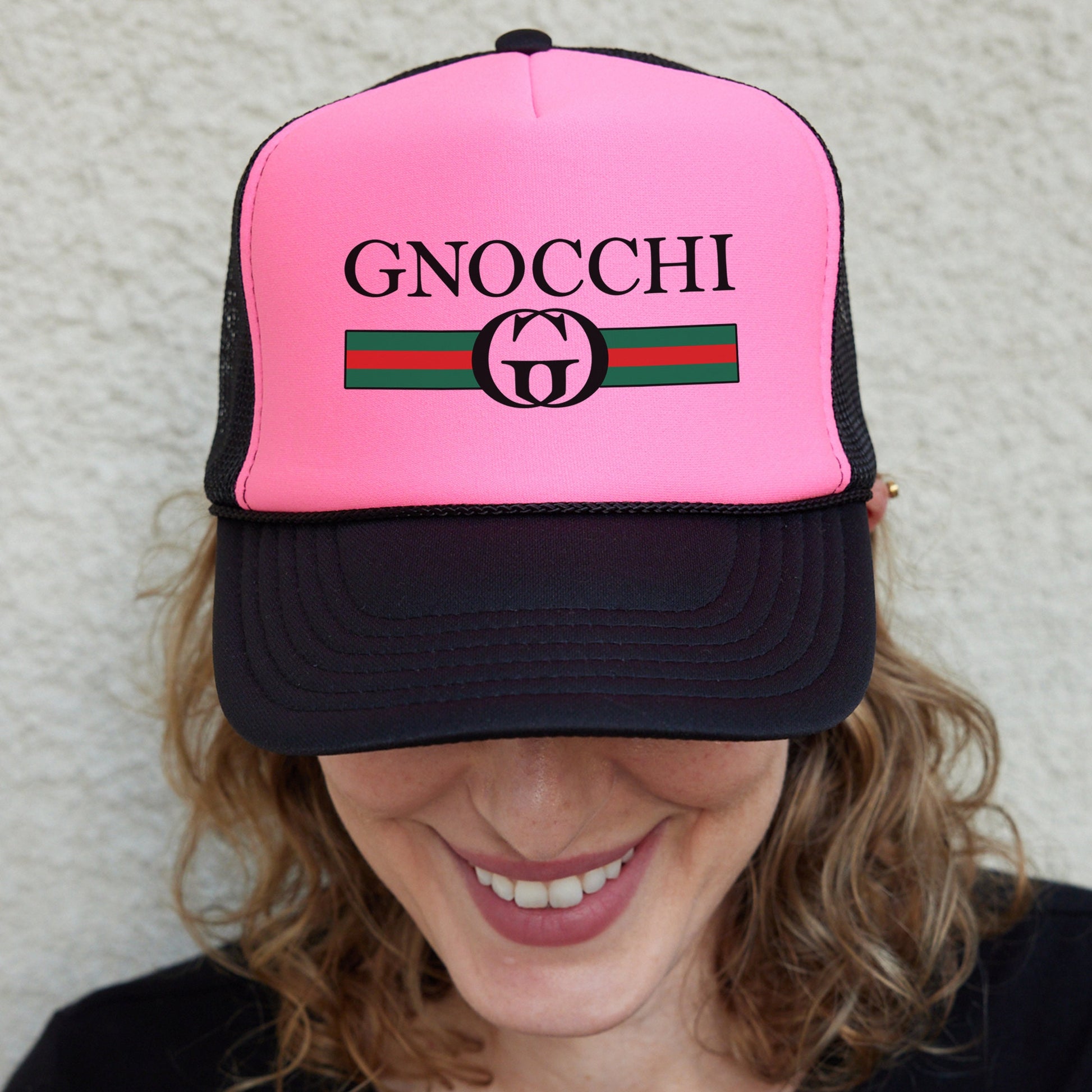 a woman wearing a pink and black hat with the word gnocchi on it