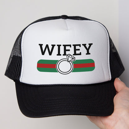 a hand holding a white and black trucker hat
