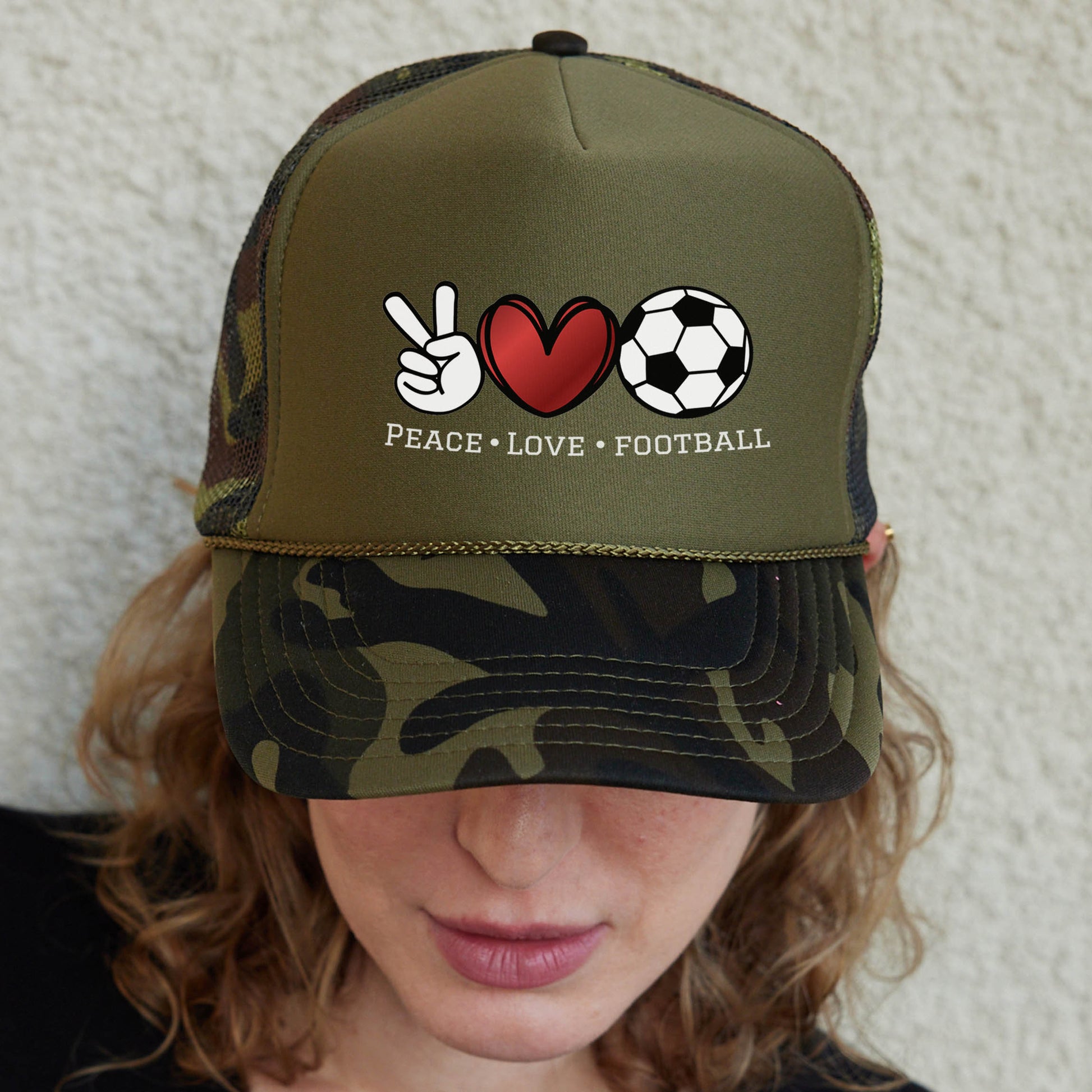 a woman wearing a camo hat with peace love football written on it