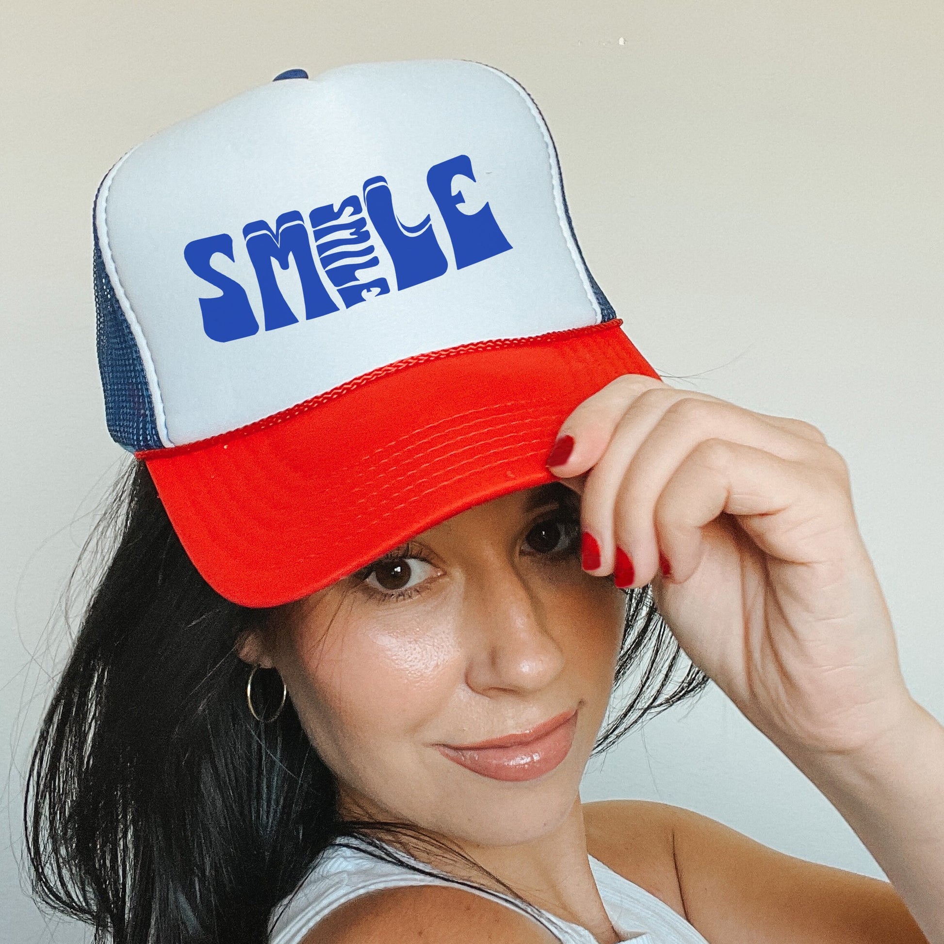 a woman in a white tank top and a red and blue hat