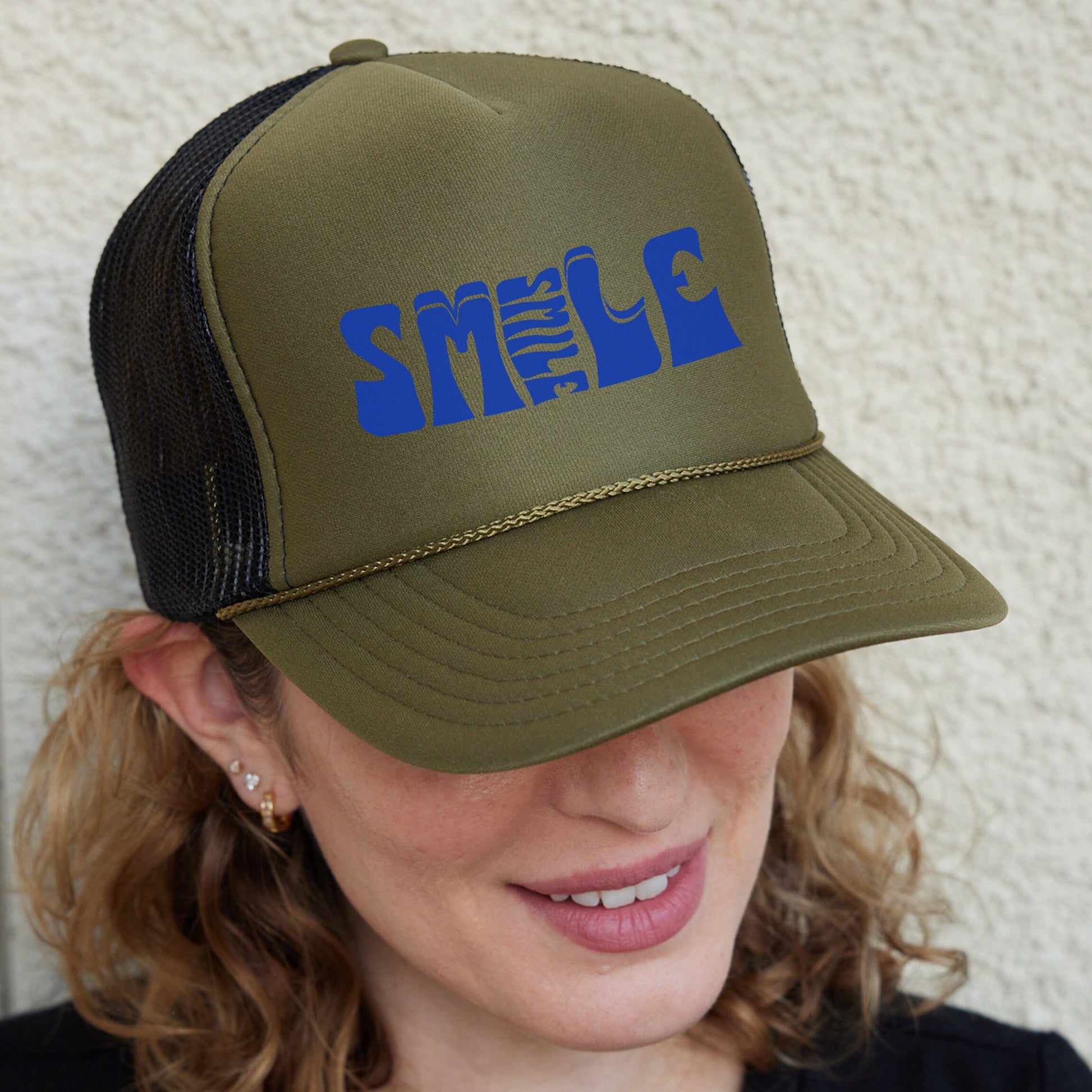 a woman wearing a green hat with blue letters on it