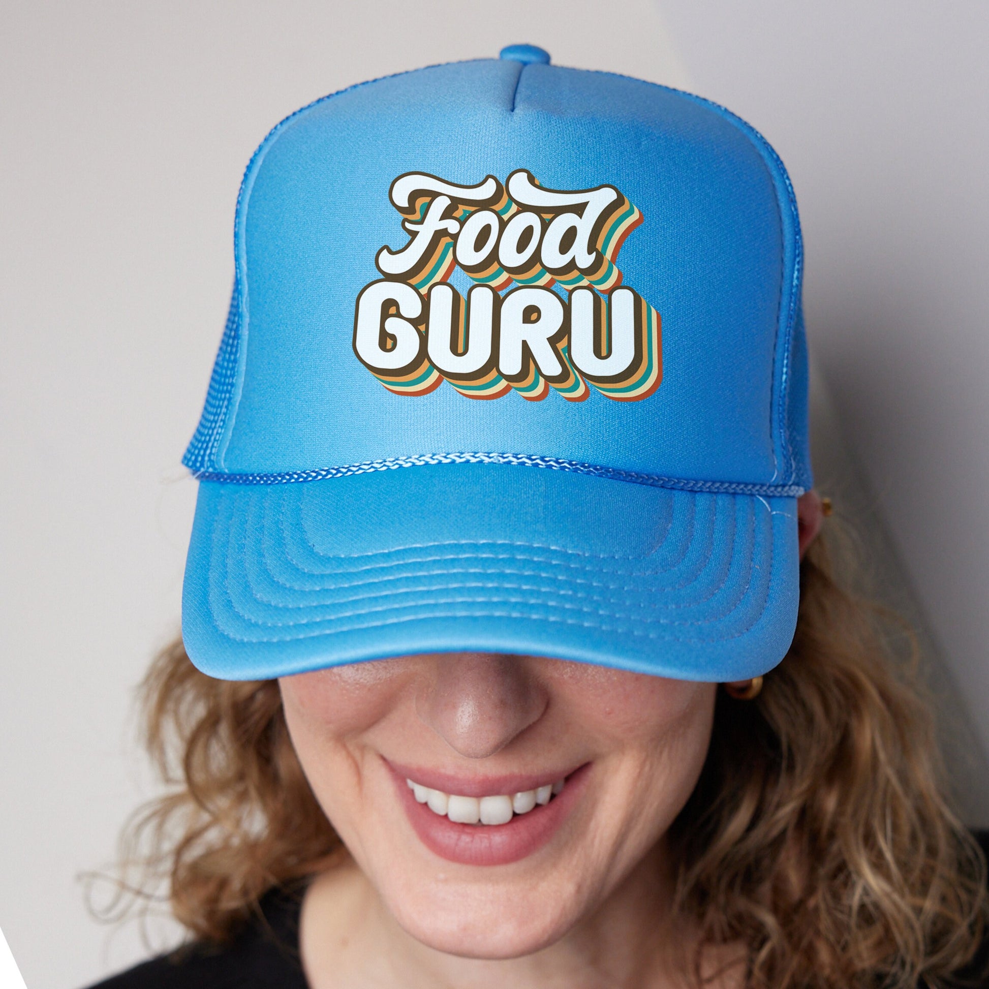 a woman wearing a blue hat with the words food guru on it