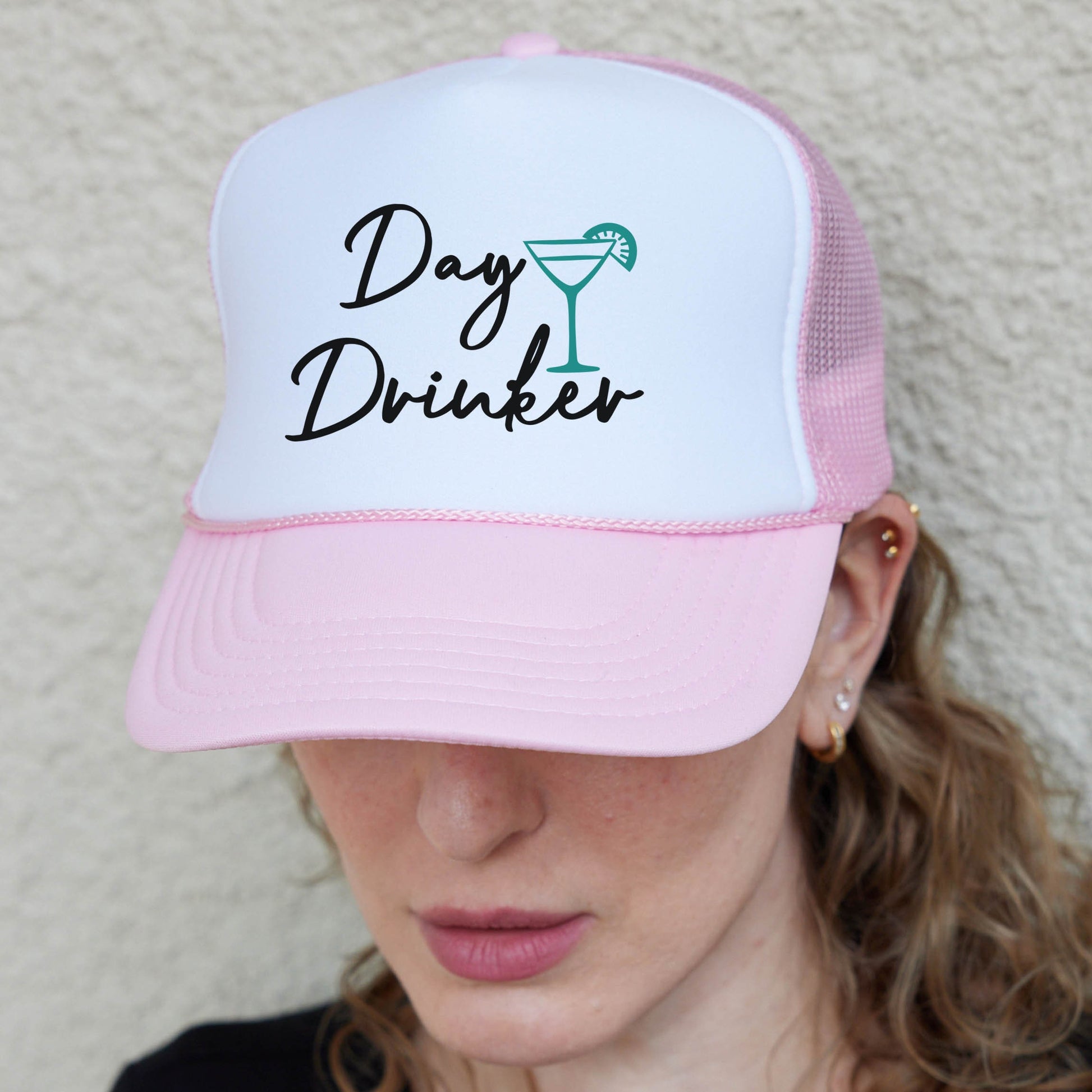 a woman wearing a pink and white hat with the words day drinker on it