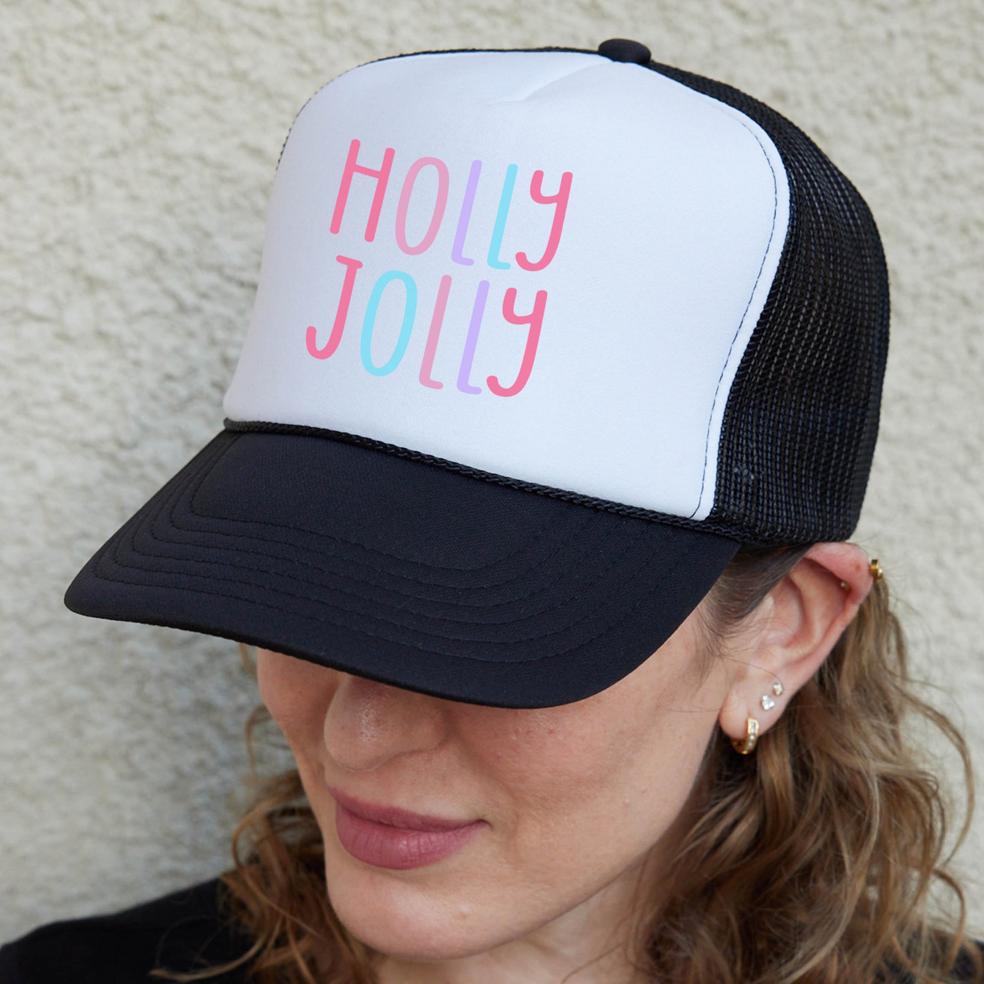 a woman wearing a black and white hat with the words holly jolly on it