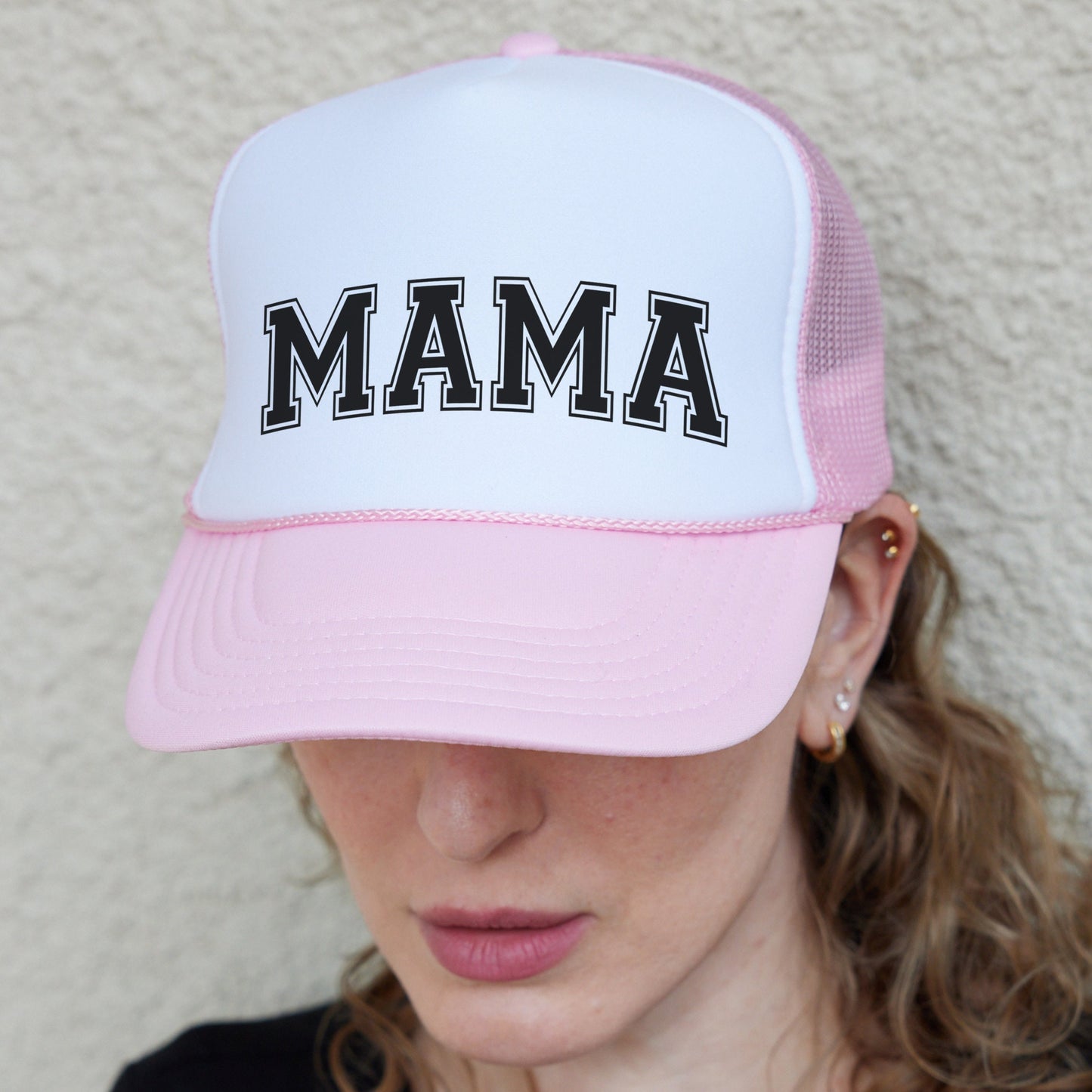 a woman wearing a pink and white hat with the word mama on it