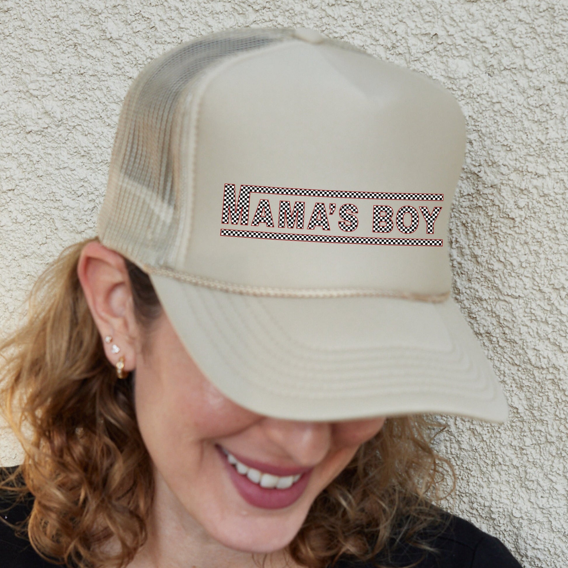 a woman wearing a tan hat with the word anas boy on it