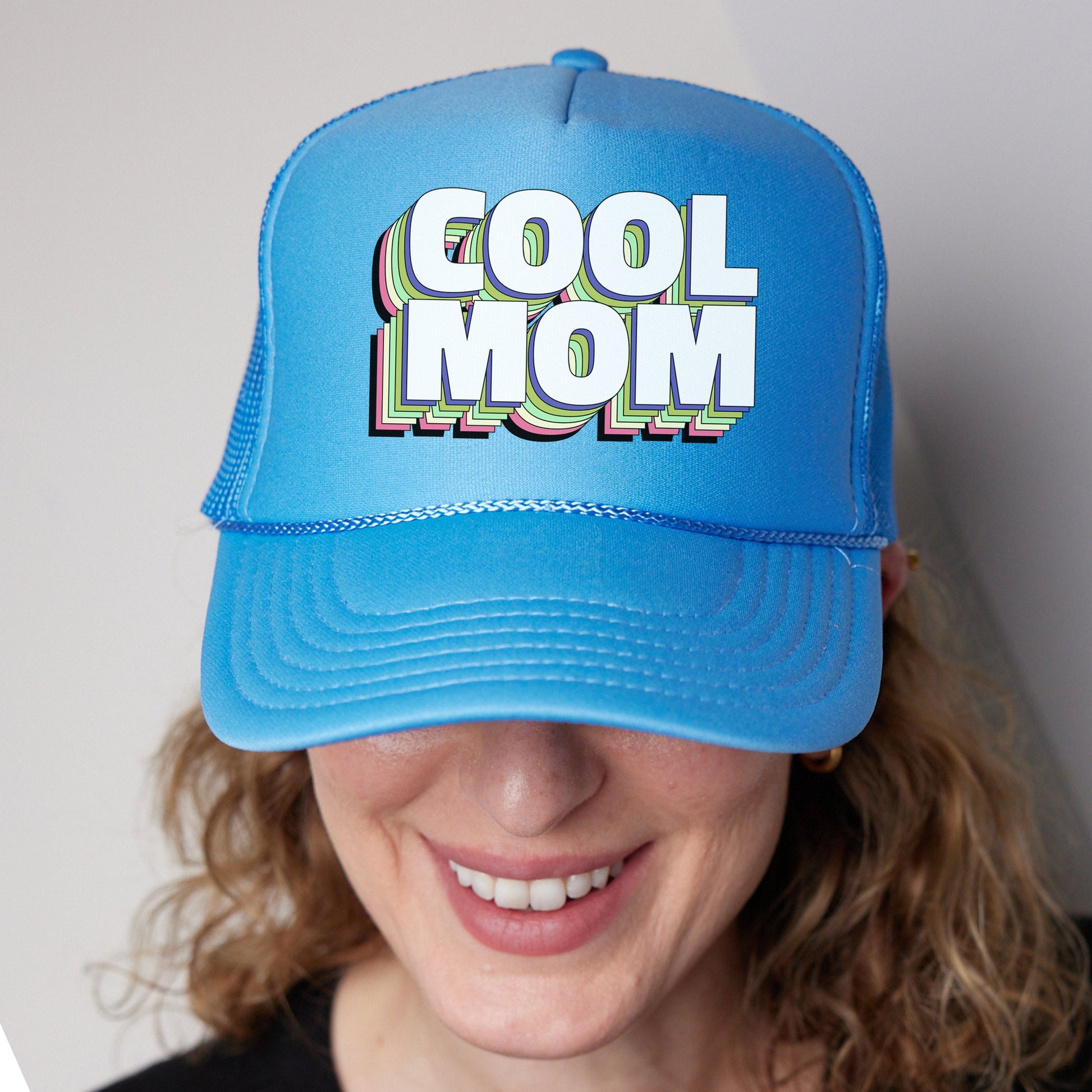 a woman wearing a blue hat with the word cool mom on it