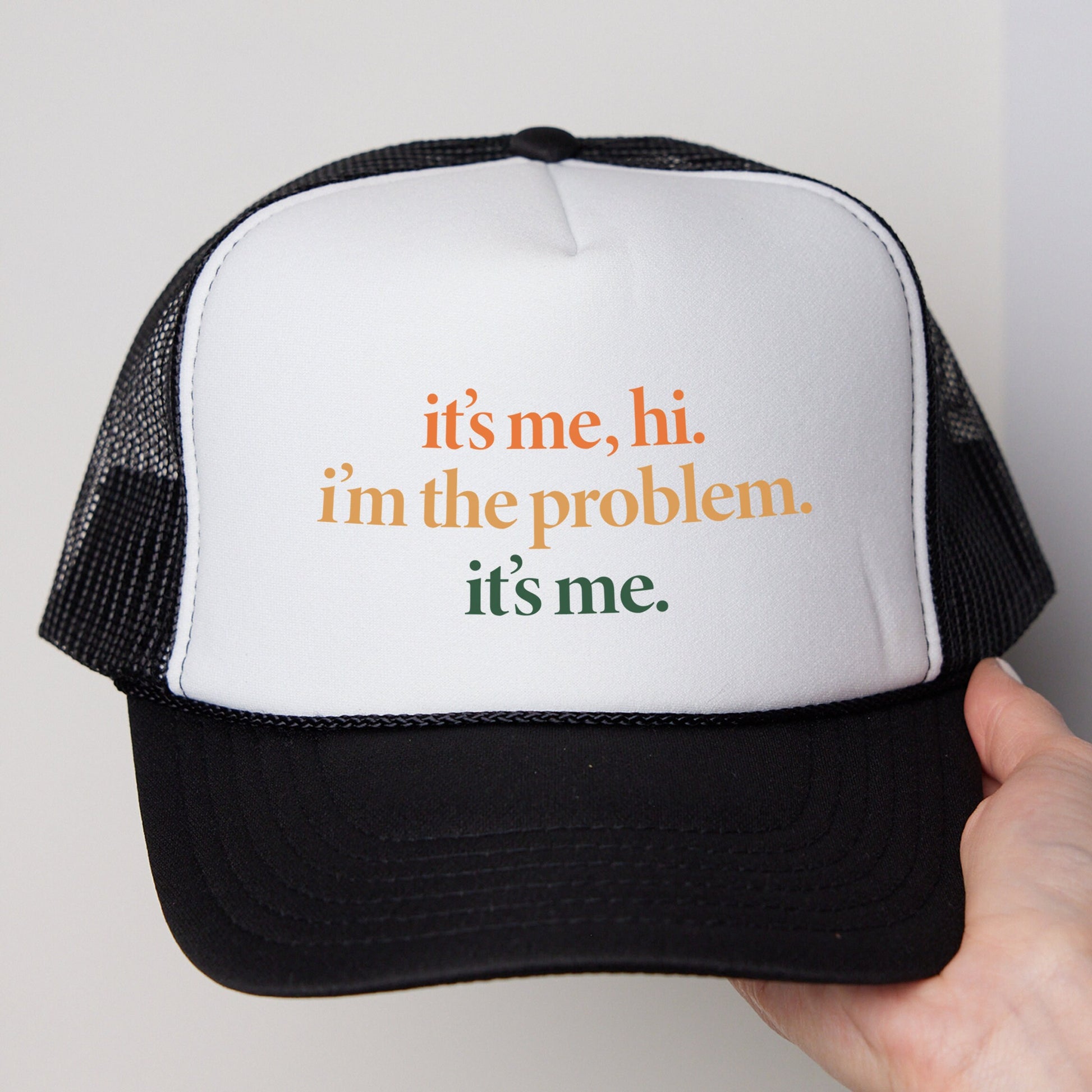 a person holding a white and black hat with the words it&#39;s me,