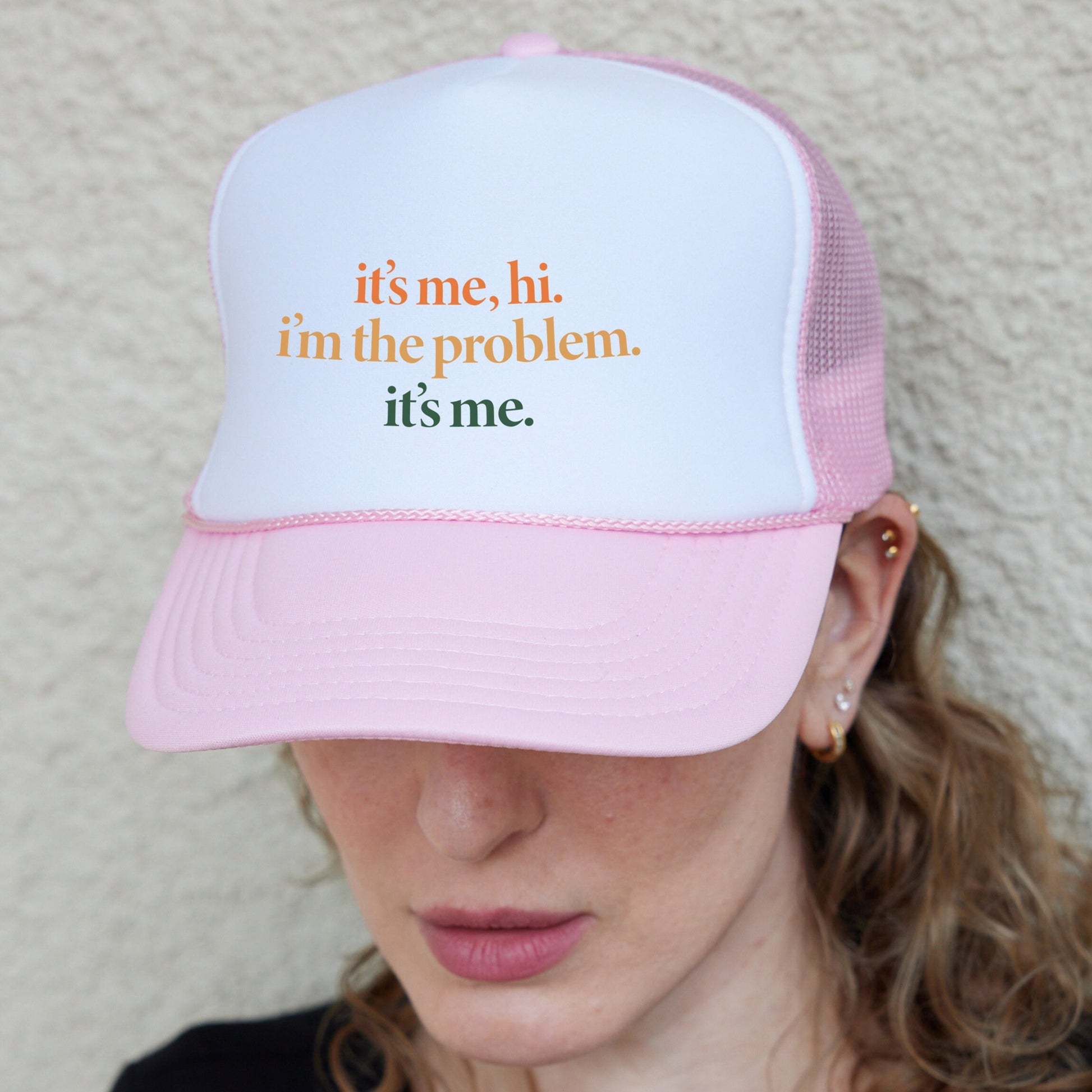 a woman wearing a pink and white hat with the words it&#39;s me,