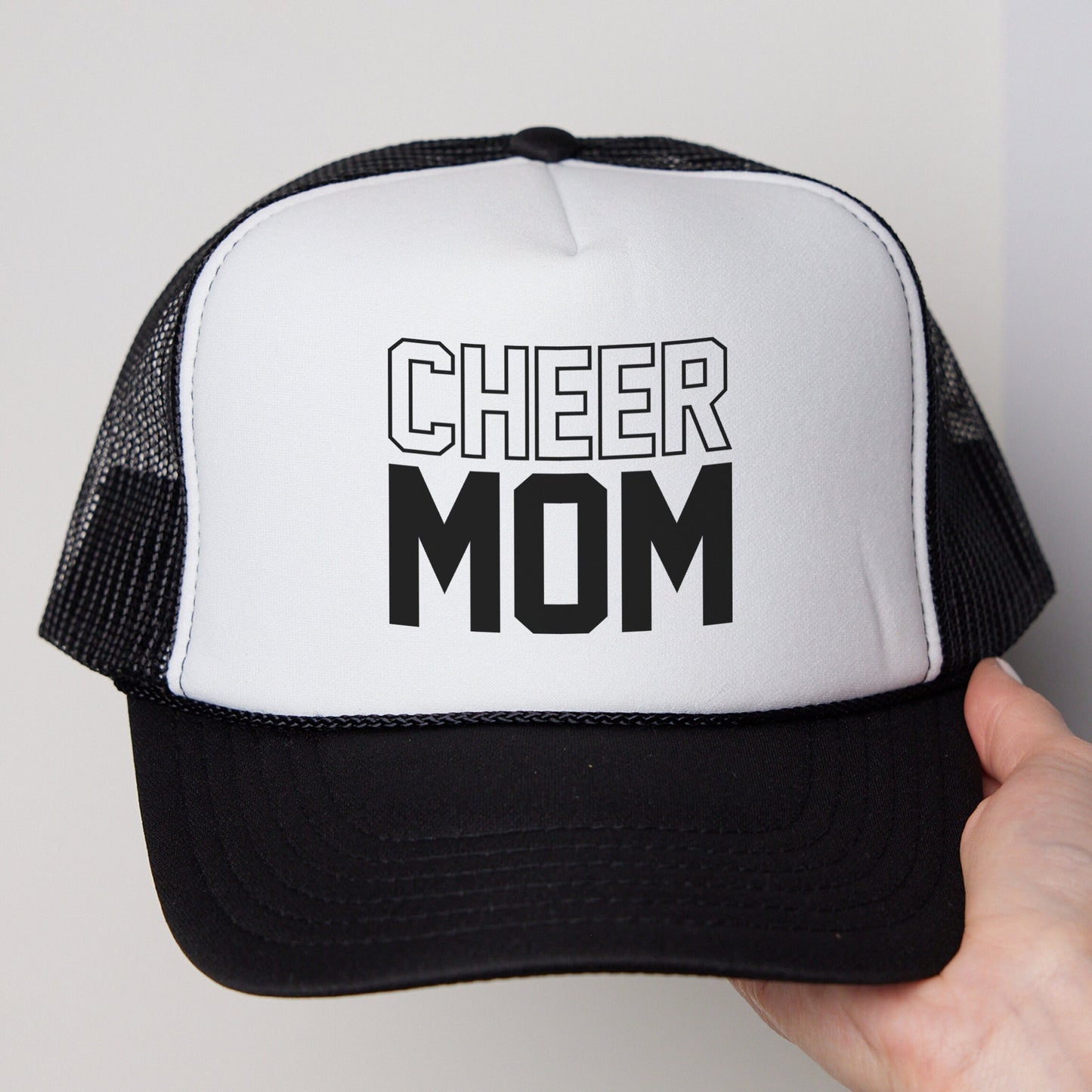 a black and white trucker hat that says cheer mom