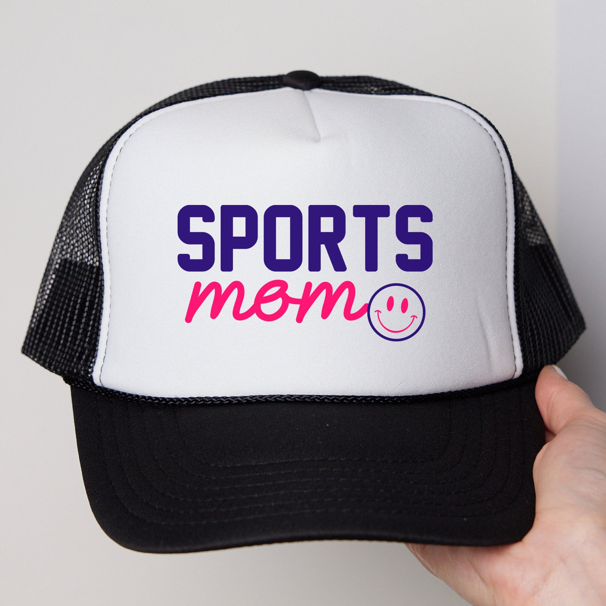 a person holding a white and black trucker hat