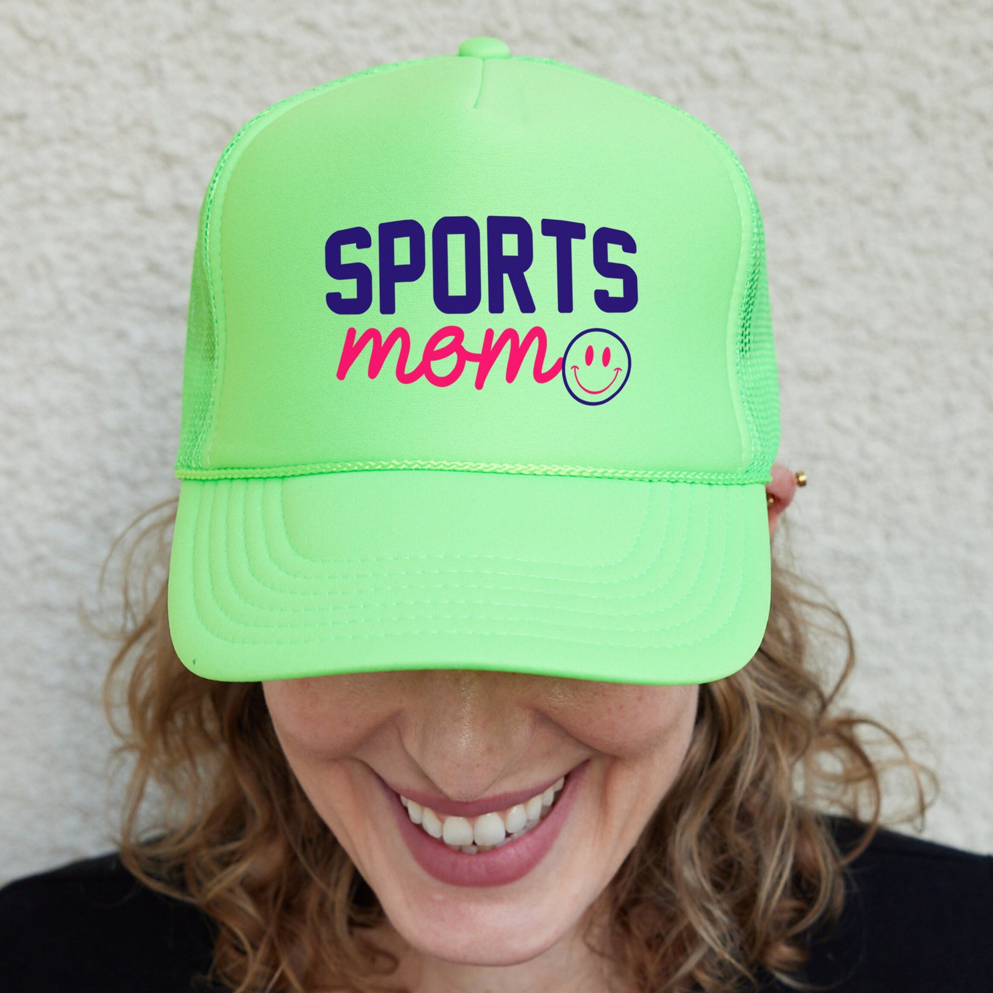 a smiling woman wearing a neon green sports hat