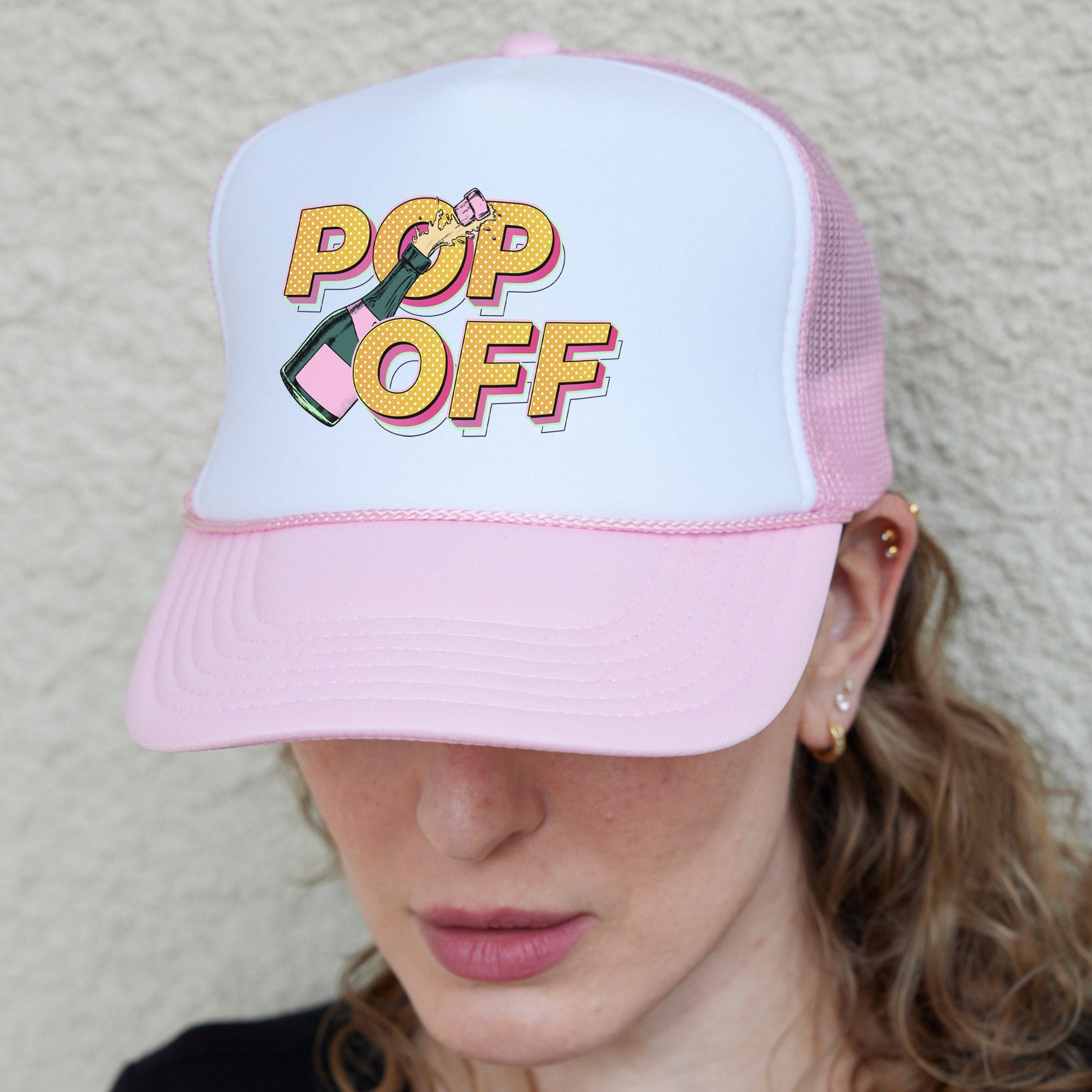 a woman wearing a pink and white hat with the words pop off on it
