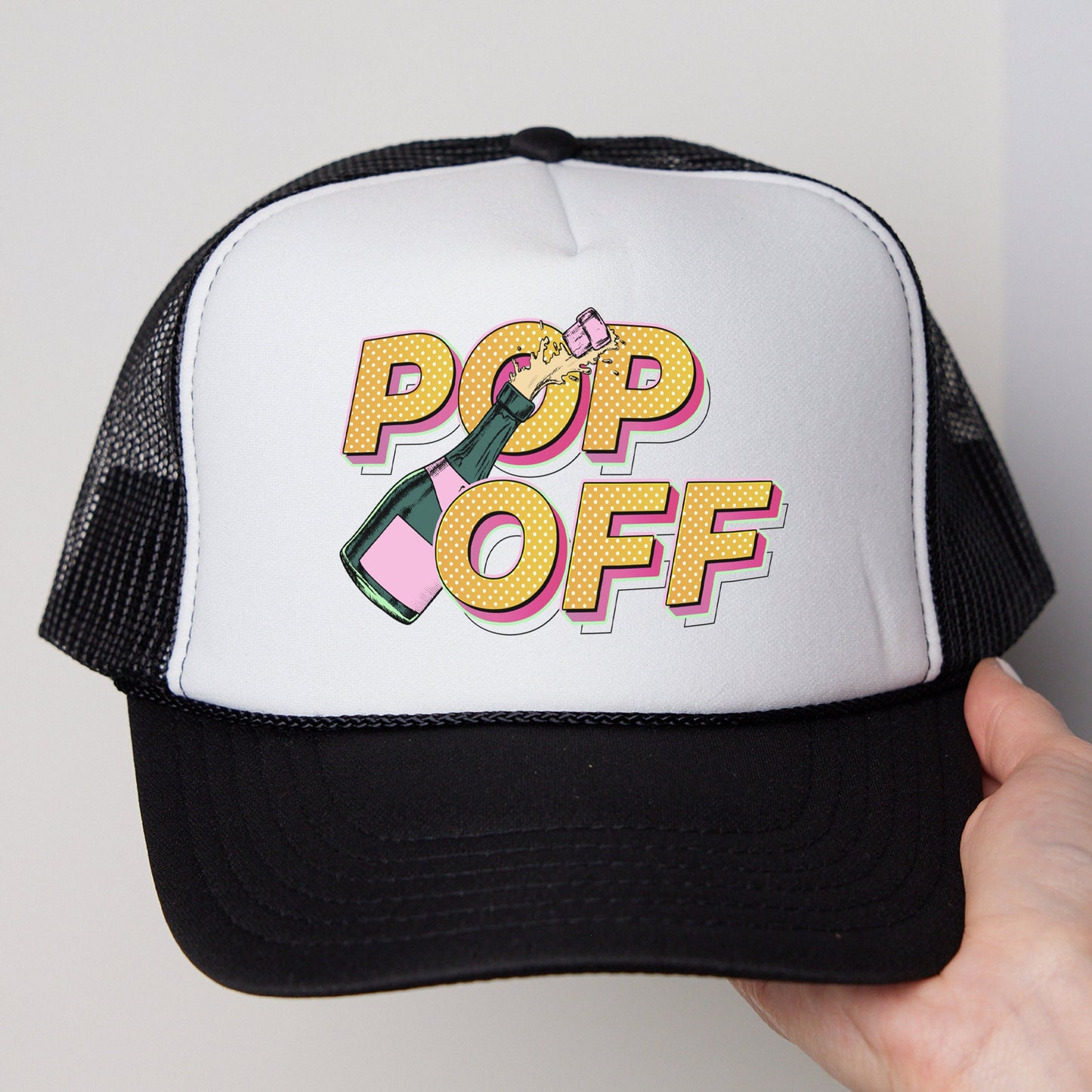 a person holding a white and black hat with pop off on it