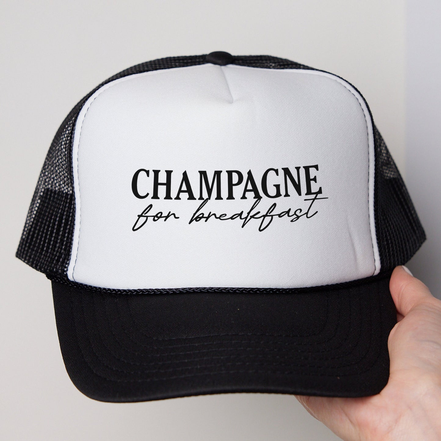 a hand holding a black and white trucker hat