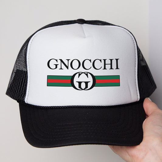 a hand holding a black and white trucker hat