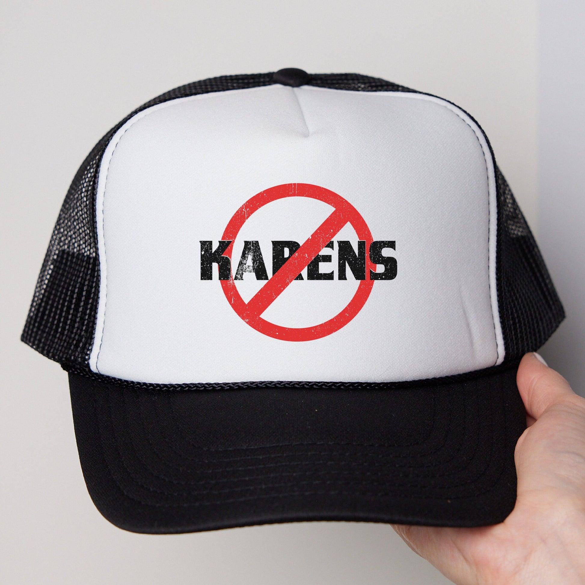 a hand holding a black and white trucker hat